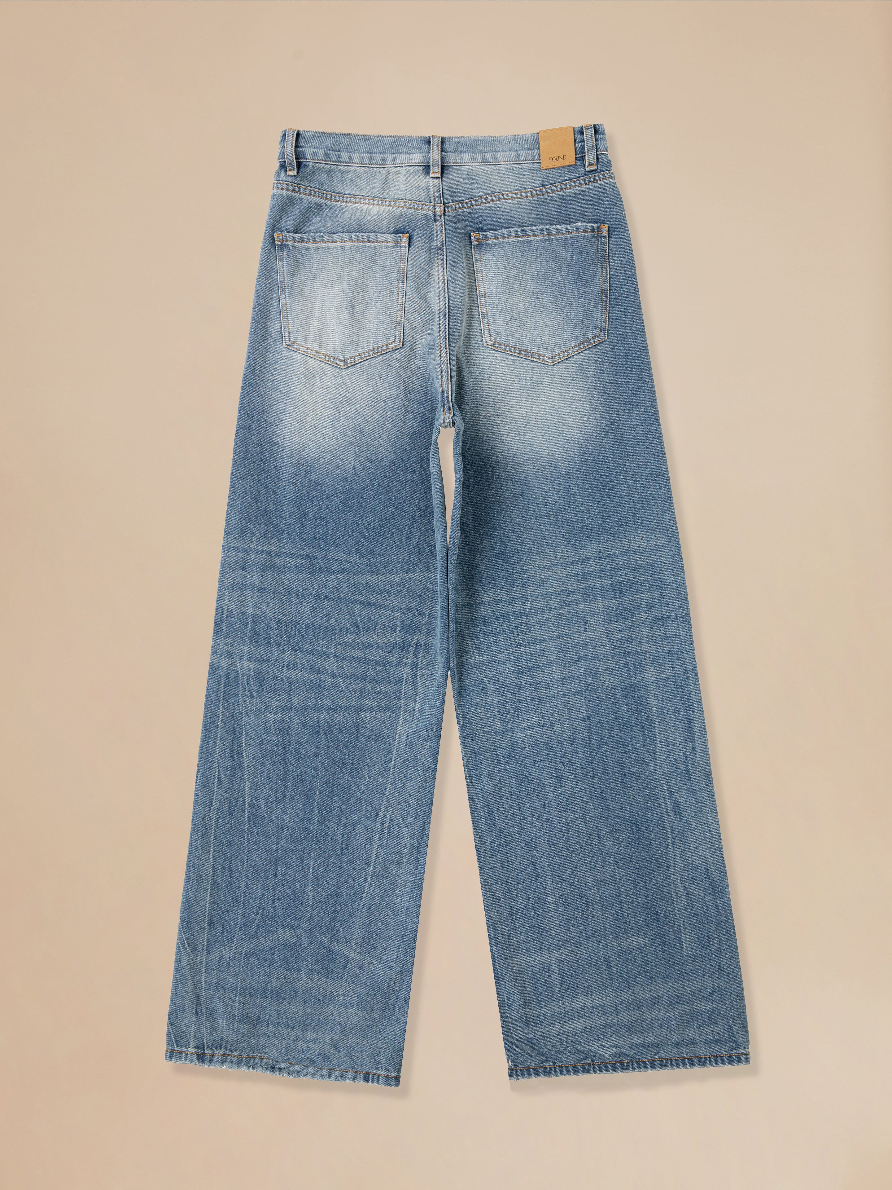 Back view of the Lacy Baggy Jeans by Found, showcasing vintage blue denim with wide legs, two back pockets, and a leather patch on the waistband. The distressed hems add a touch of rugged charm.