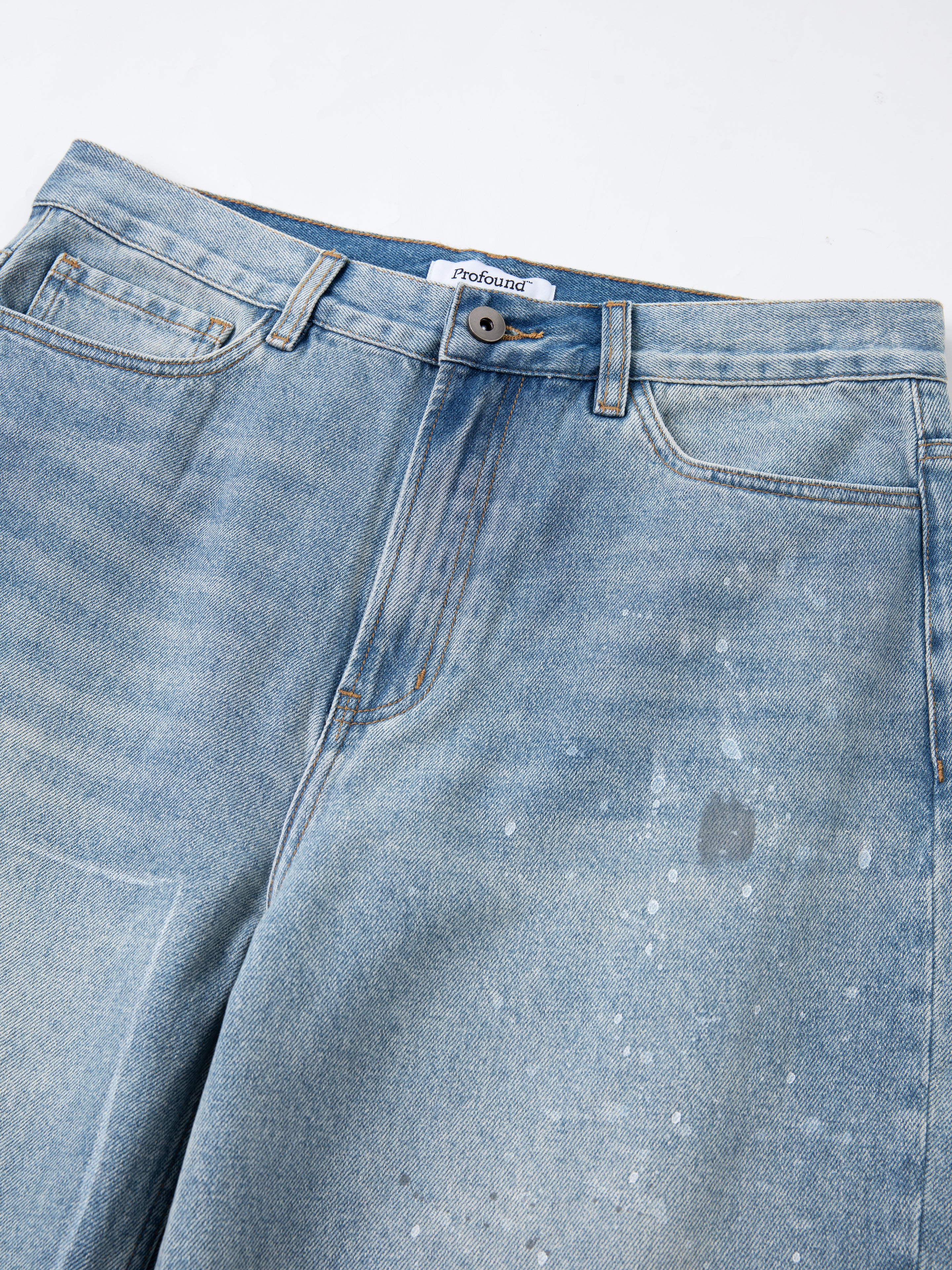 The Mix Patch Jeans by Profound feature a faded blue wash with a paint splatter design, button closure, and front pockets, all crafted from premium denim cotton for a soft touch.