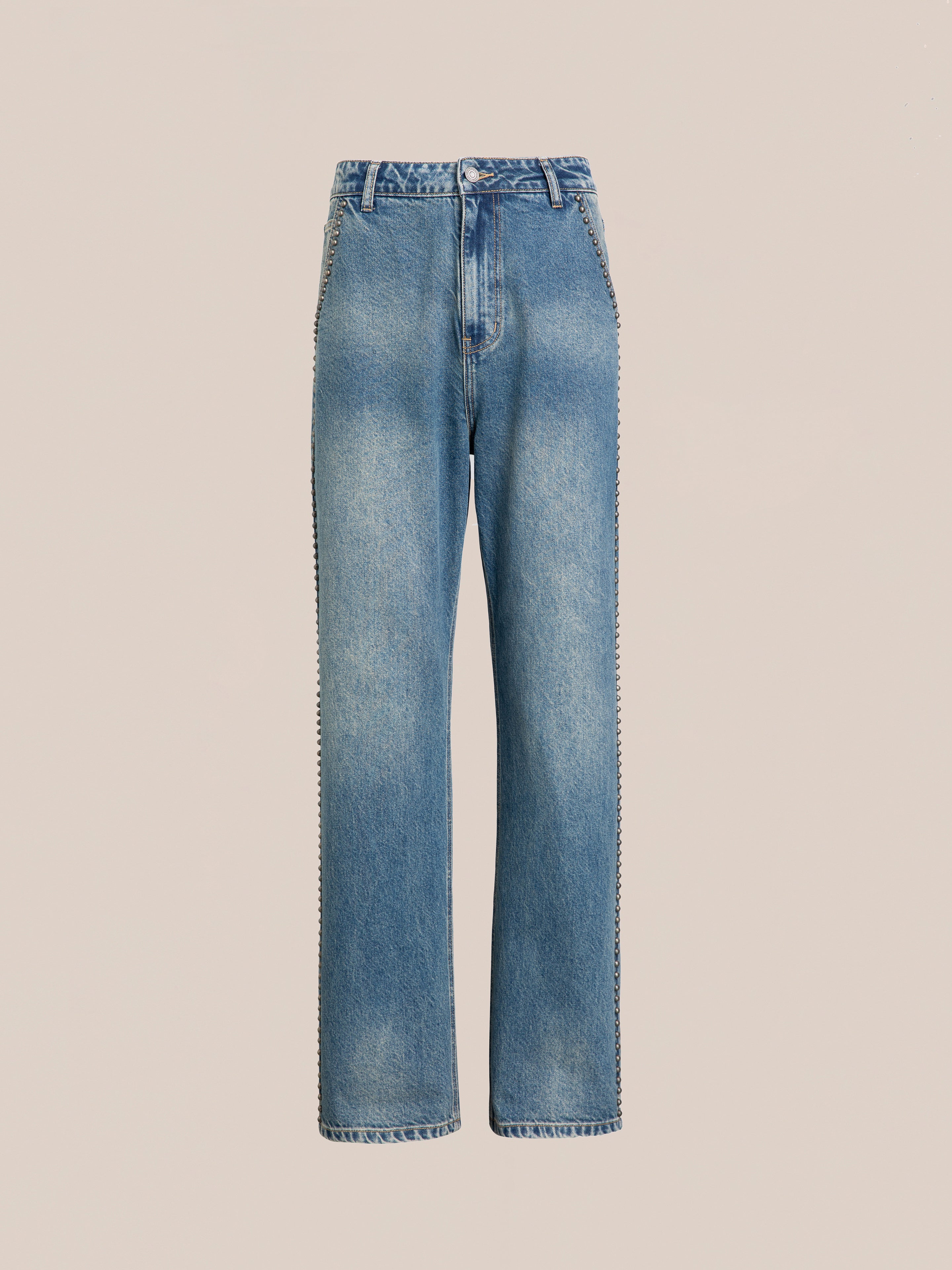 The Azar Studded Jeans by FOUND are high-waisted, straight-leg blue jeans in a vintage blue wash, featuring a button and zip fly and adorned with antique matte silver studs, displayed against a plain beige background.