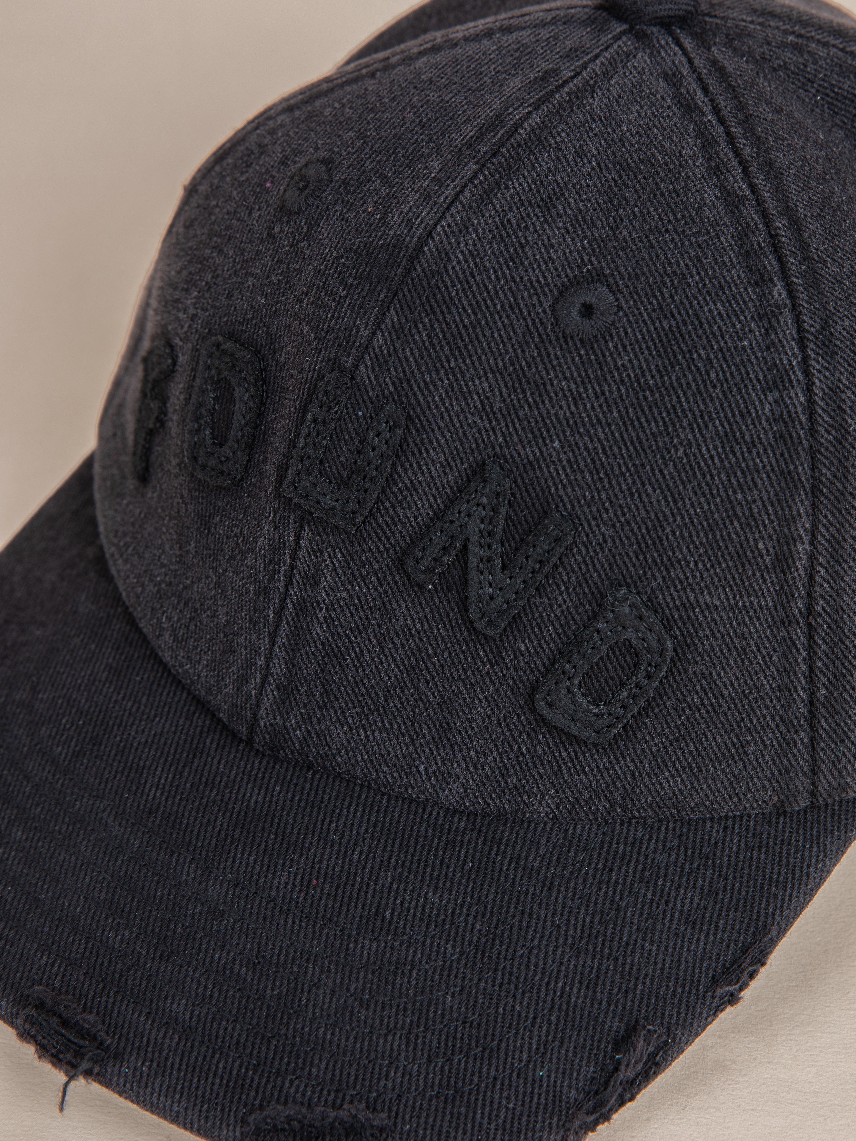 The Black Felt Patch Cap by FOUND showcases the word "FOUND" embroidered boldly on its front in dark letters. Its distressed brim enhances its timeless appeal, making it an ideal accessory for casual outings.