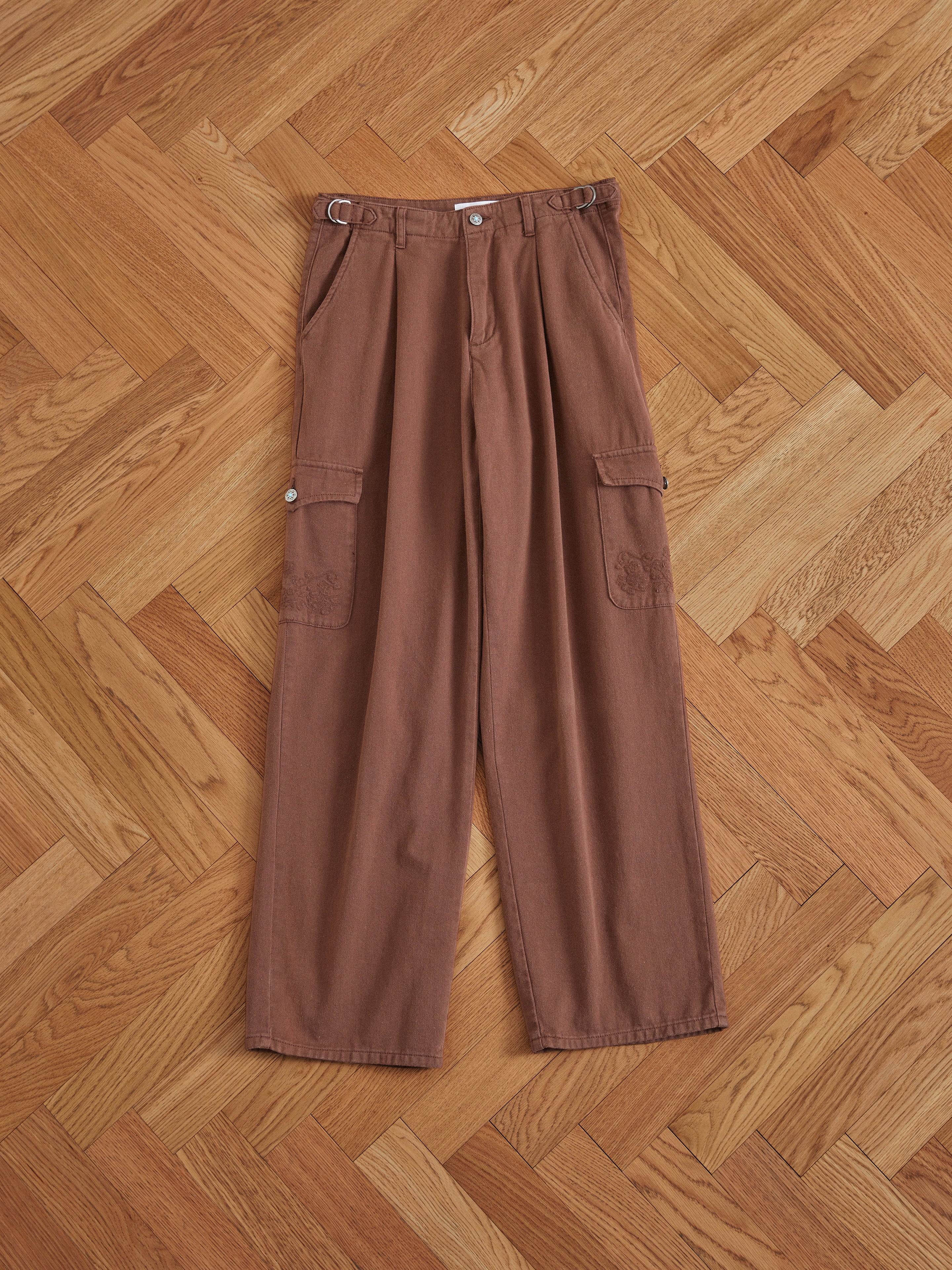 A pair of Found Dusky Western Cargo Jeans on a wooden floor.