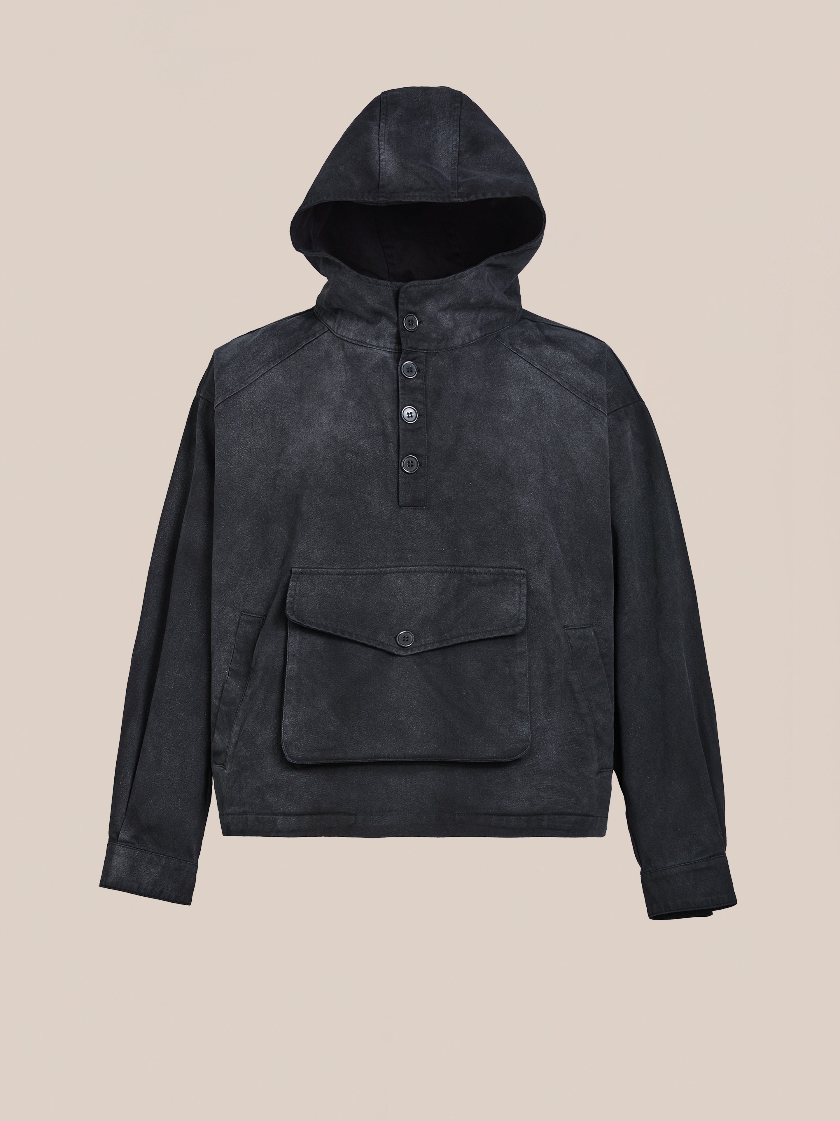 The FOUND Washed Twill Pocket Anorak Jacket offers a relaxed fit unisex design with a cotton twill texture, hood, buttoned front placket, and large flap pocket in vintage black.