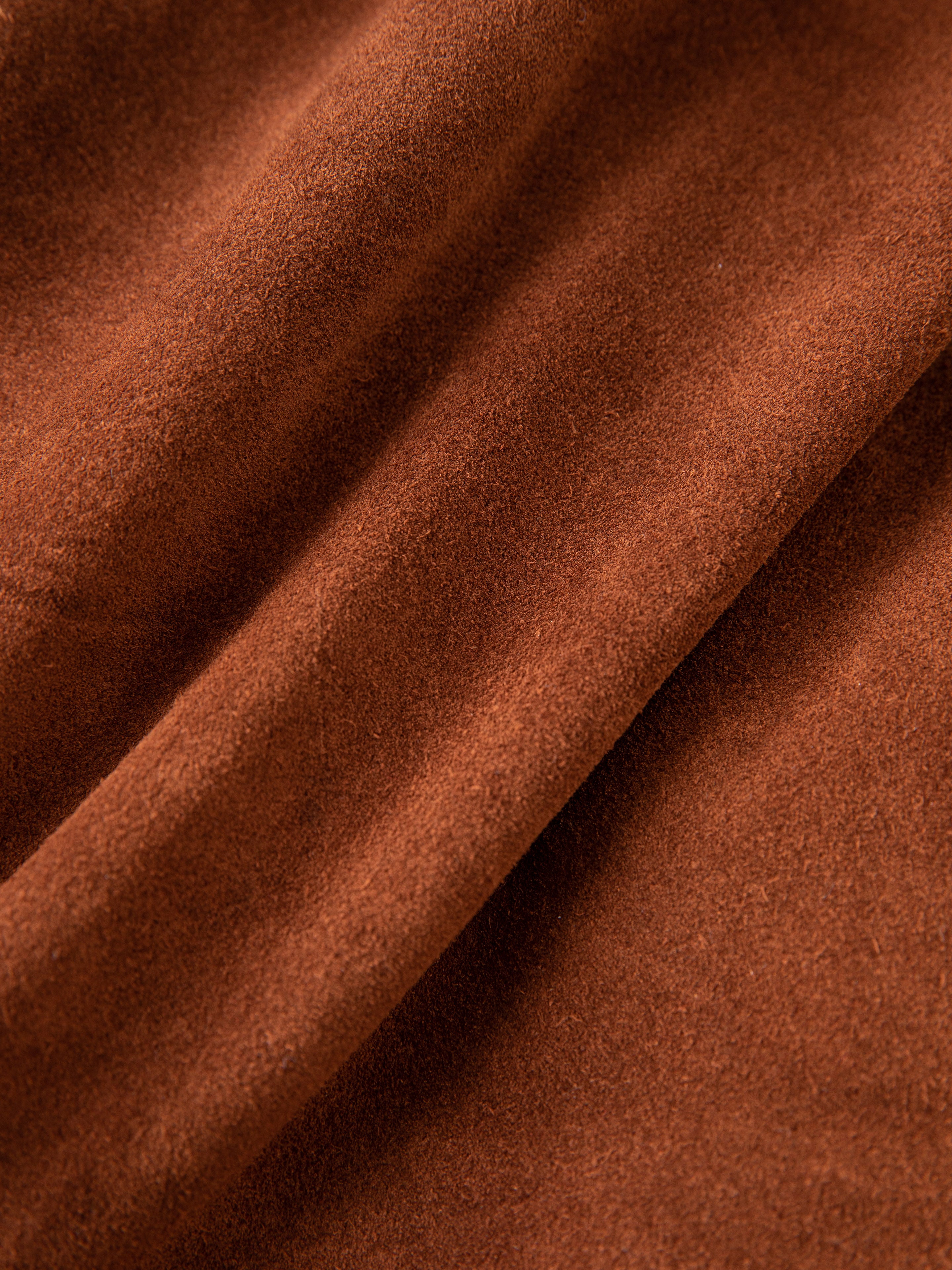 Close-up of ethically produced brown suede fabric by FOUND showcases a smooth texture and gentle folds, ideal for the Double Breasted Suede Leather Jacket, perfect for unisex wear.