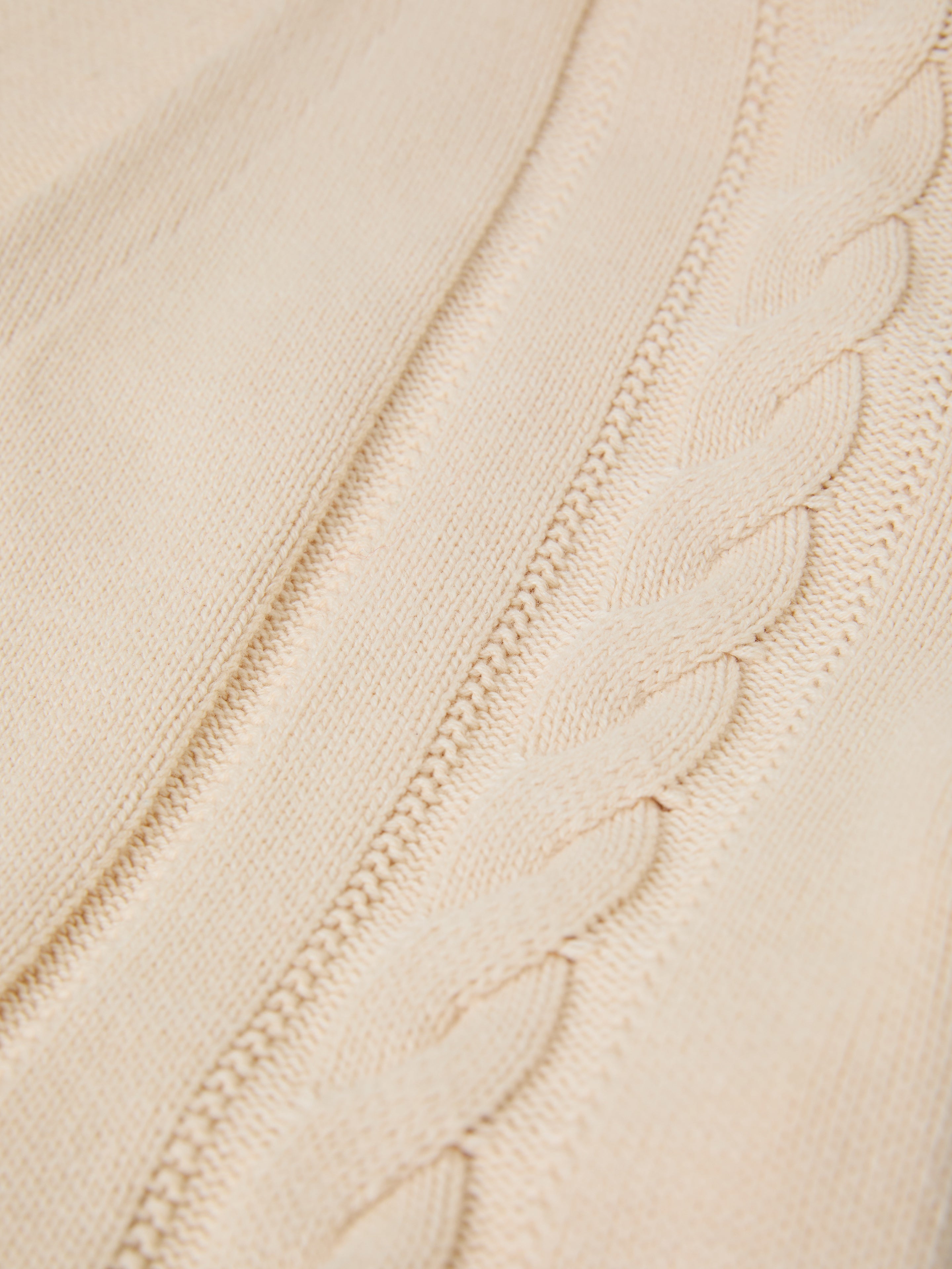 Close-up of a Double Breasted Knit Cardigan by FOUND, featuring a beige cable-knit fabric with a braided and textured pattern, crafted from a soft cotton blend.