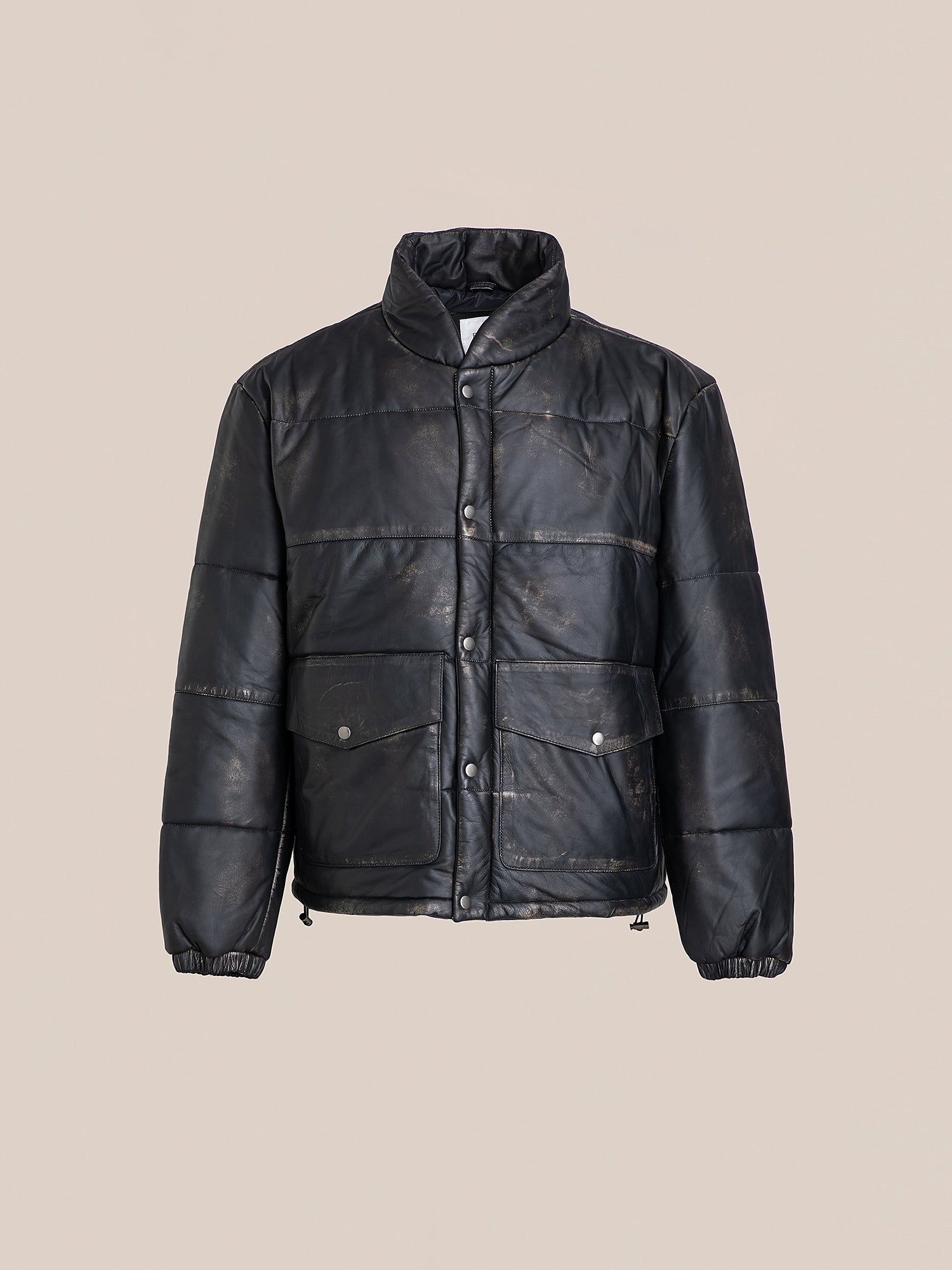 The Leather Distressed Puffer Jacket by FOUND features a black color with a high collar, front buttons, and two large pockets. It is made from ethically sourced materials, presented on a neutral background.