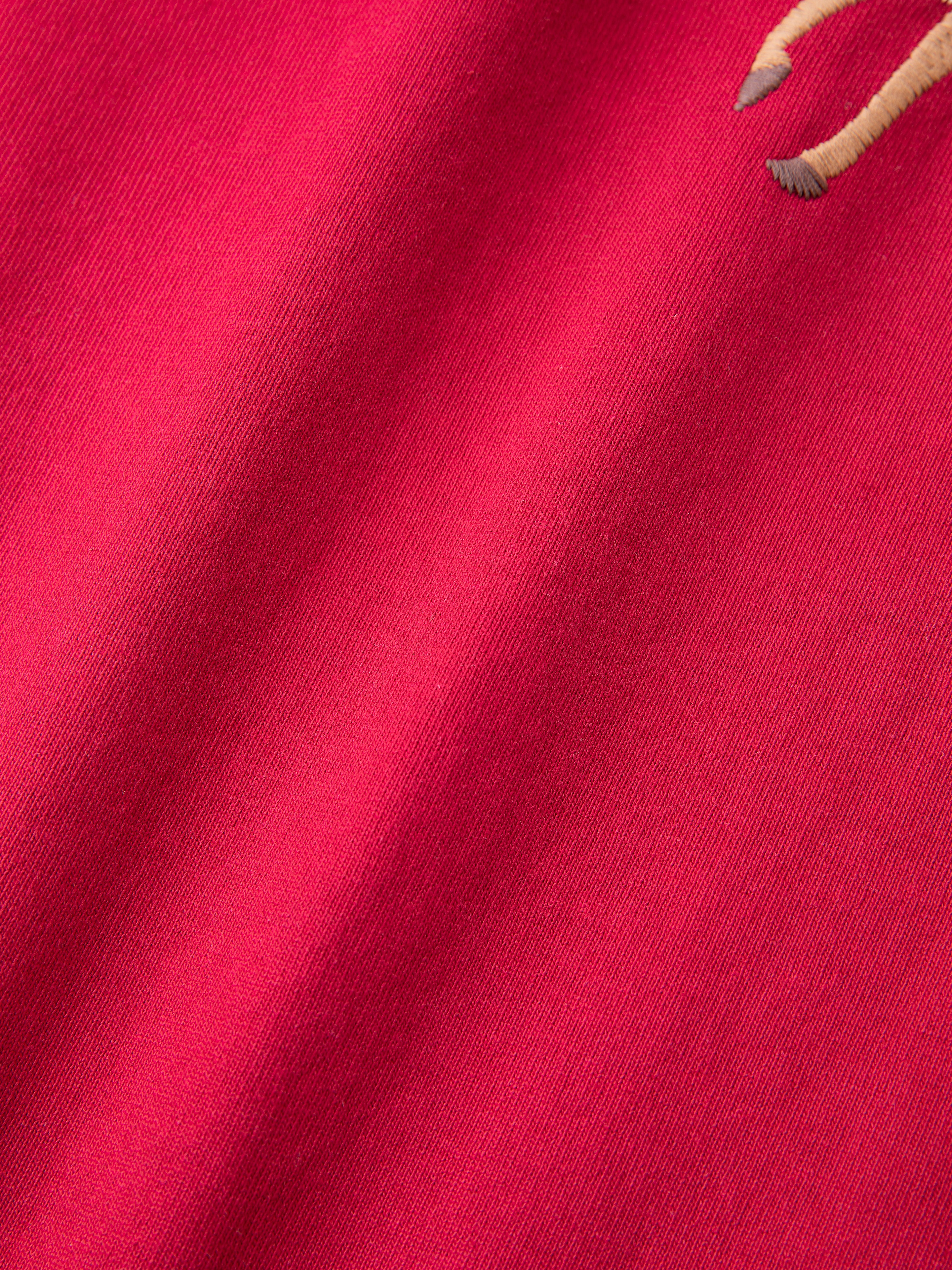 Close-up of a Horse Equine Tee by FOUND, showcasing its vibrant racing red color with a small embroidered detail on the upper right.