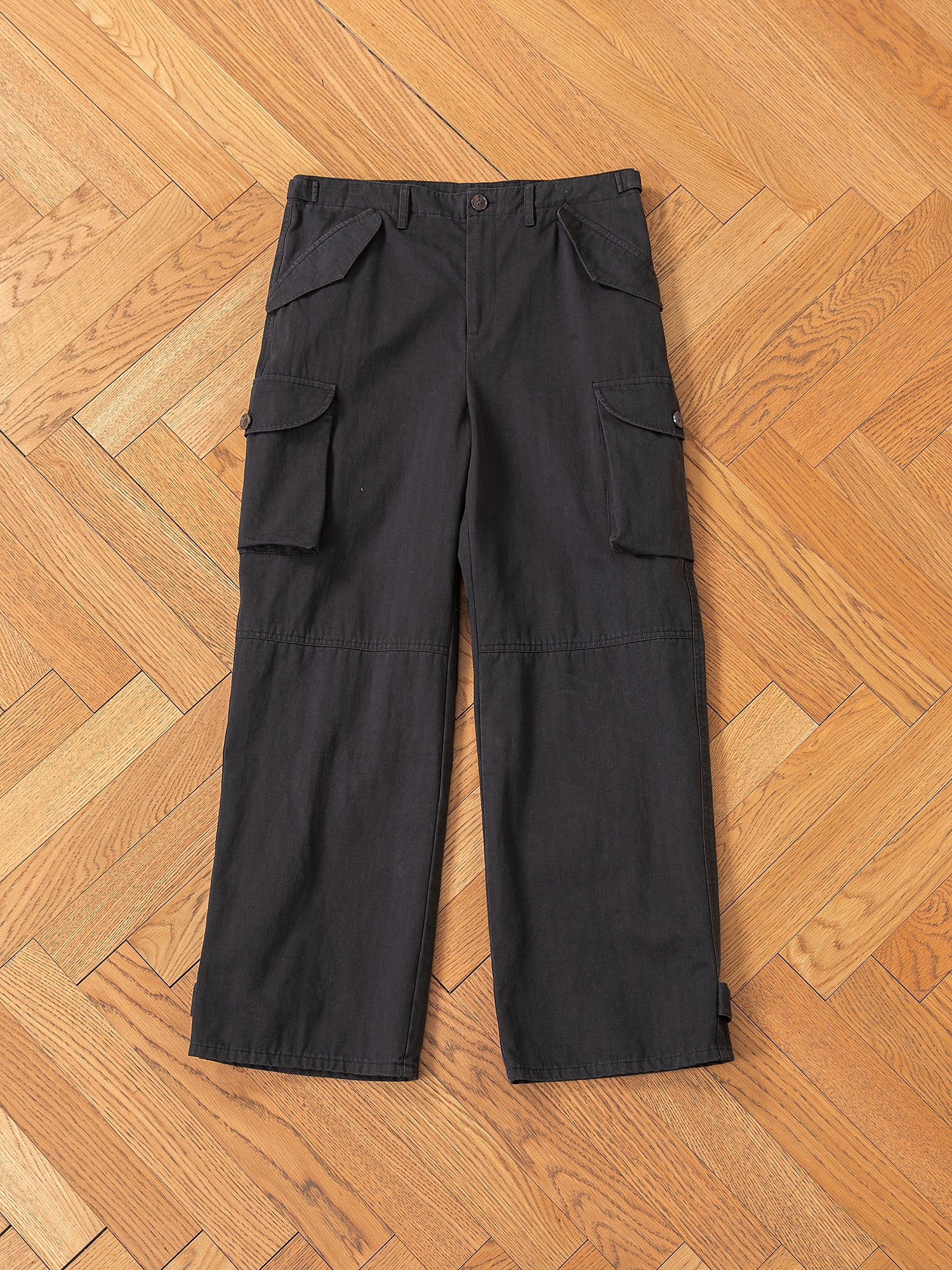 FOUND's Utility Herringbone Cargo Pants in vintage-look black are crafted from durable cotton twill, featuring multiple pockets and are displayed on a hardwood floor.