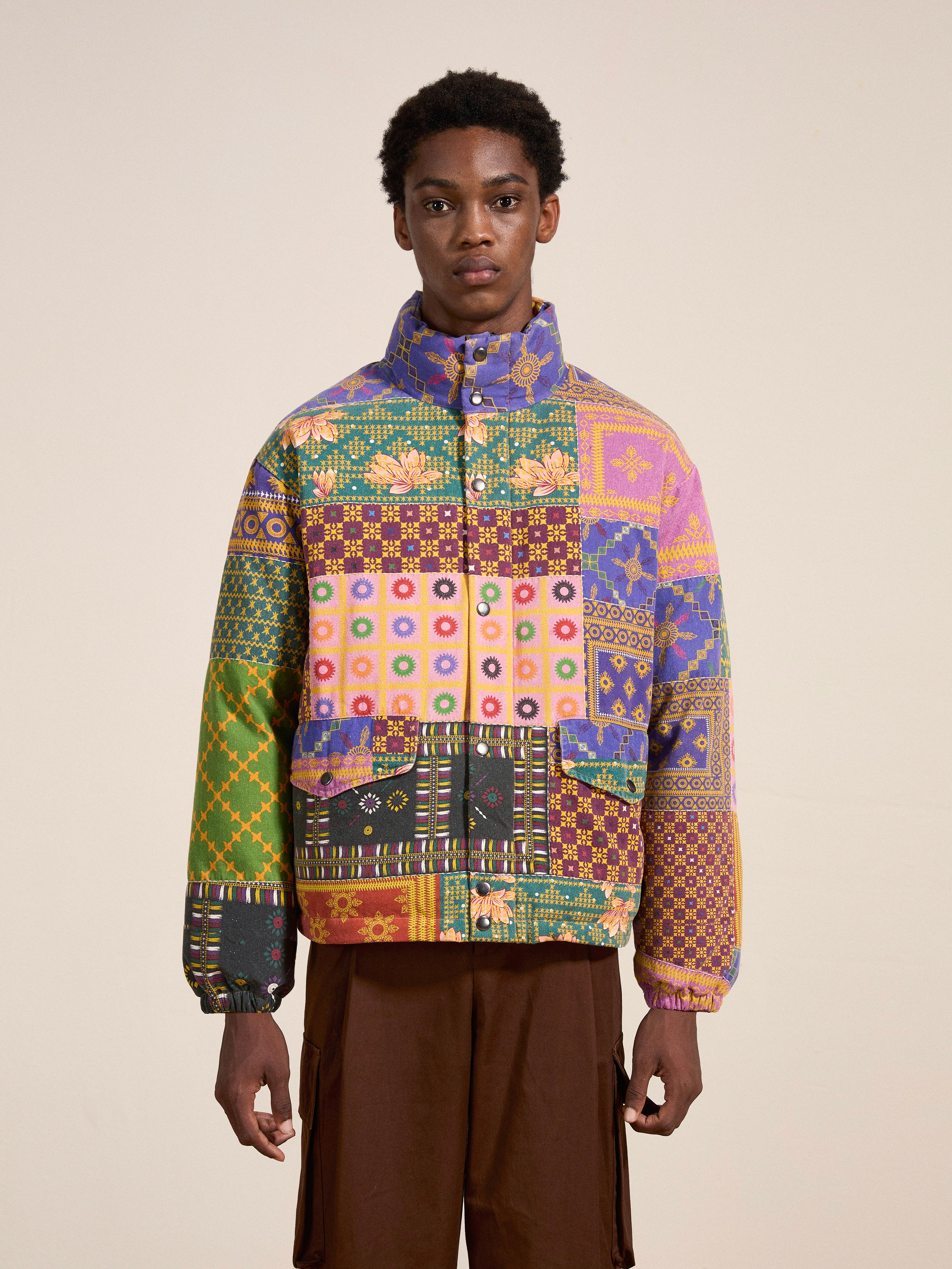 A person wearing the Ayubia Printed Tapestry Puffer Jacket by FOUND and brown cargo pants, standing against a plain background.