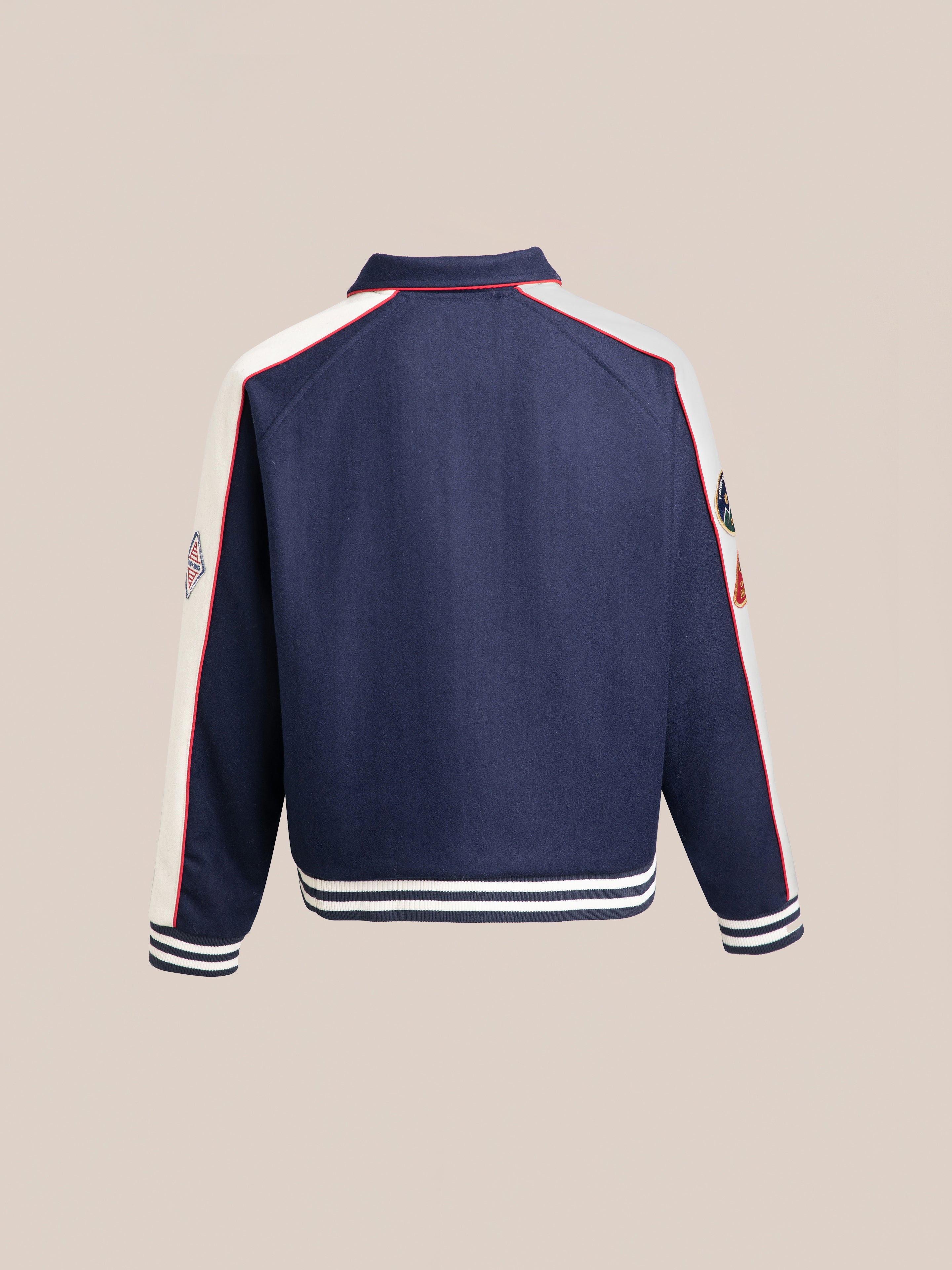 Back view of the FOUND All Roads Varsity Jacket in navy blue, accented with white and red details on the sleeves and collar, and featuring white and red striped cuffs and hem. Made from a mid-weight wool blend, this jacket exudes a vintage charm.