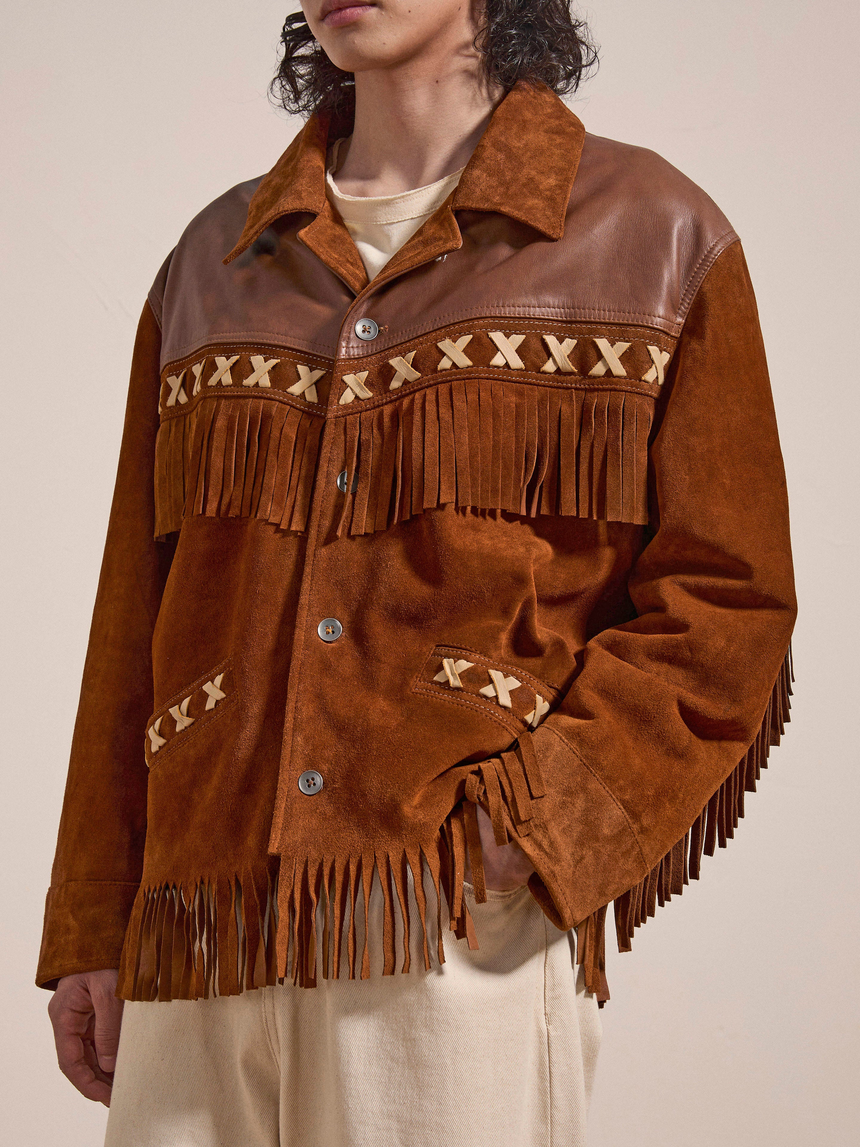 A person dons FOUND's Western Fringe Suede Leather Jacket with decorative patterns over a beige shirt, merging style with ethically sourced materials.