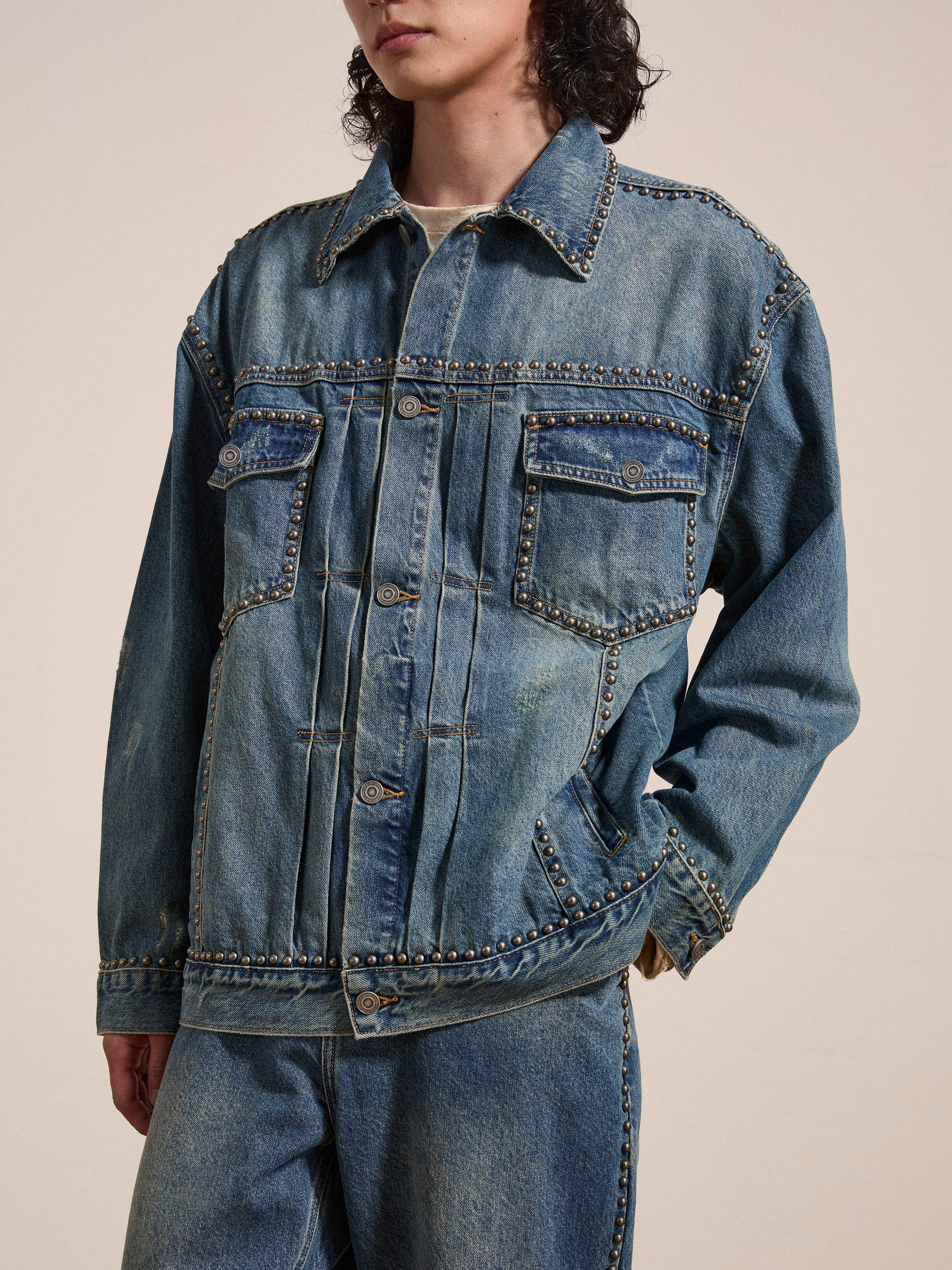 Individual sporting a FOUND Azar Studded Denim Trucker Jacket in a vintage blue wash with metal buttons, paired with matching oversized boxy fit jeans.