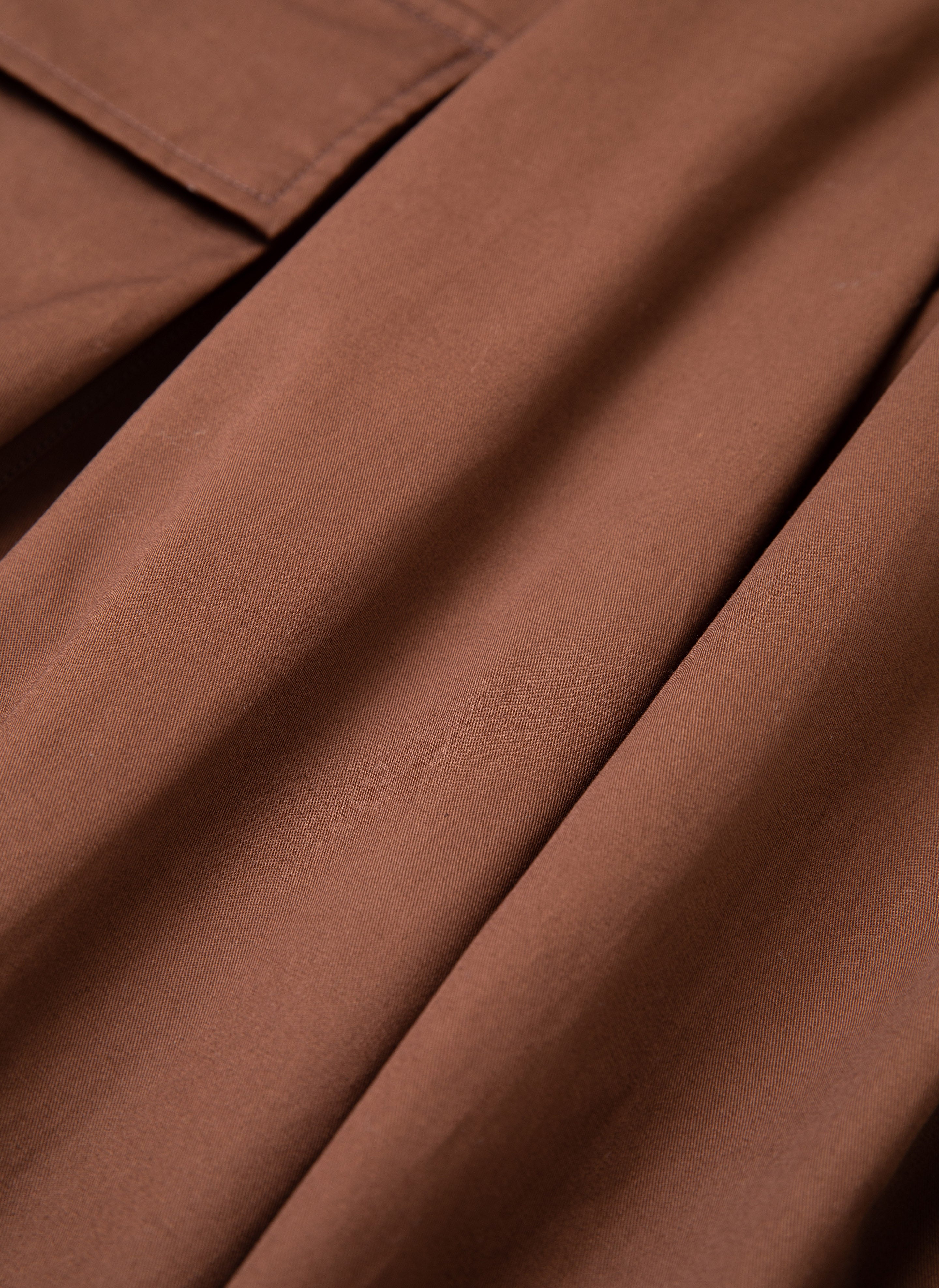 Close-up of brown fabric, showcasing the texture and pleats of FOUND's Pleated Pocket Trousers.