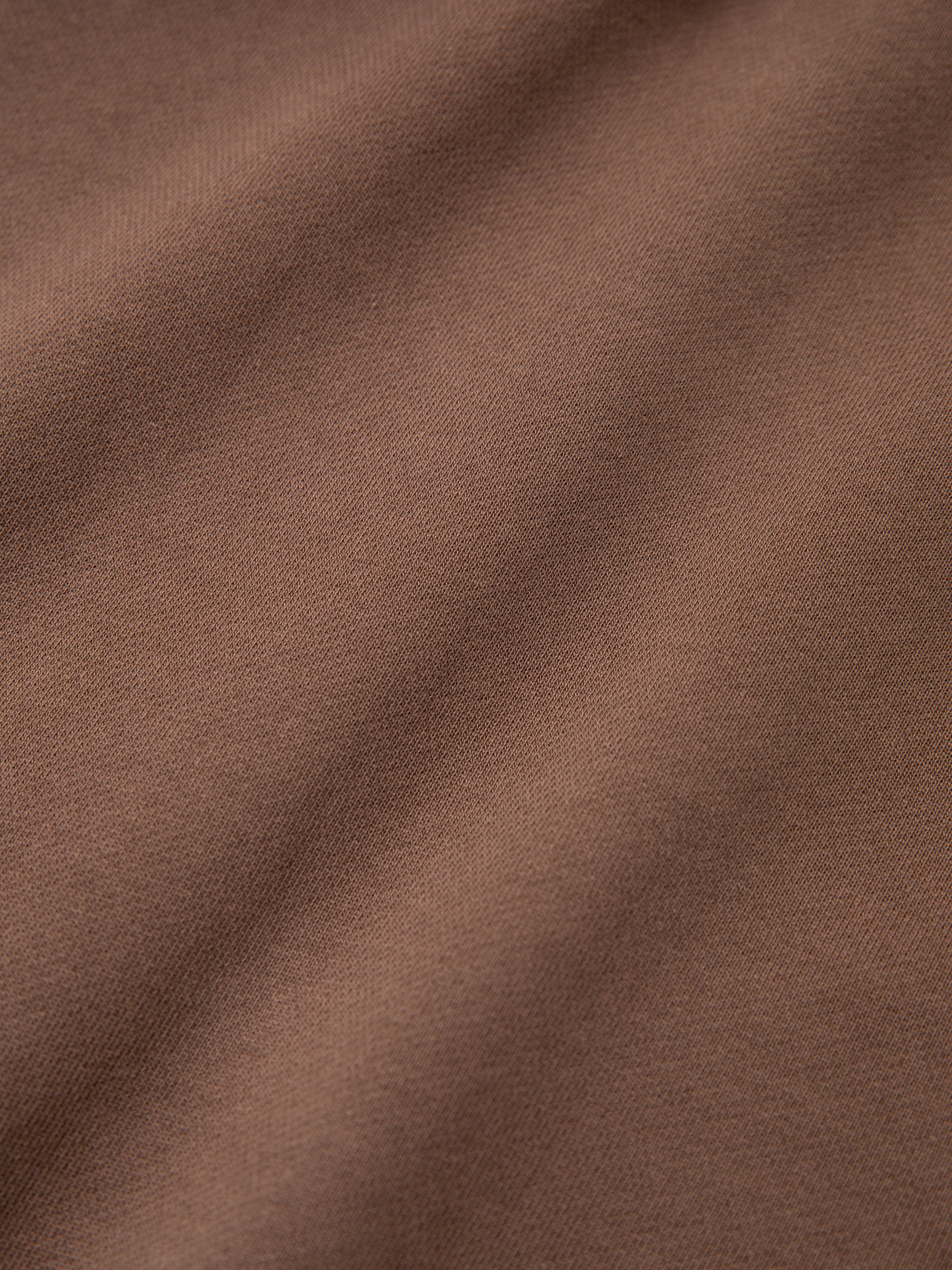 Close-up image of the brown French Terry Cotton fabric on the Quarter Zip Two Tone Hoodie by FOUND, displaying soft, textured folds running diagonally across the surface, giving it a vintage feel.