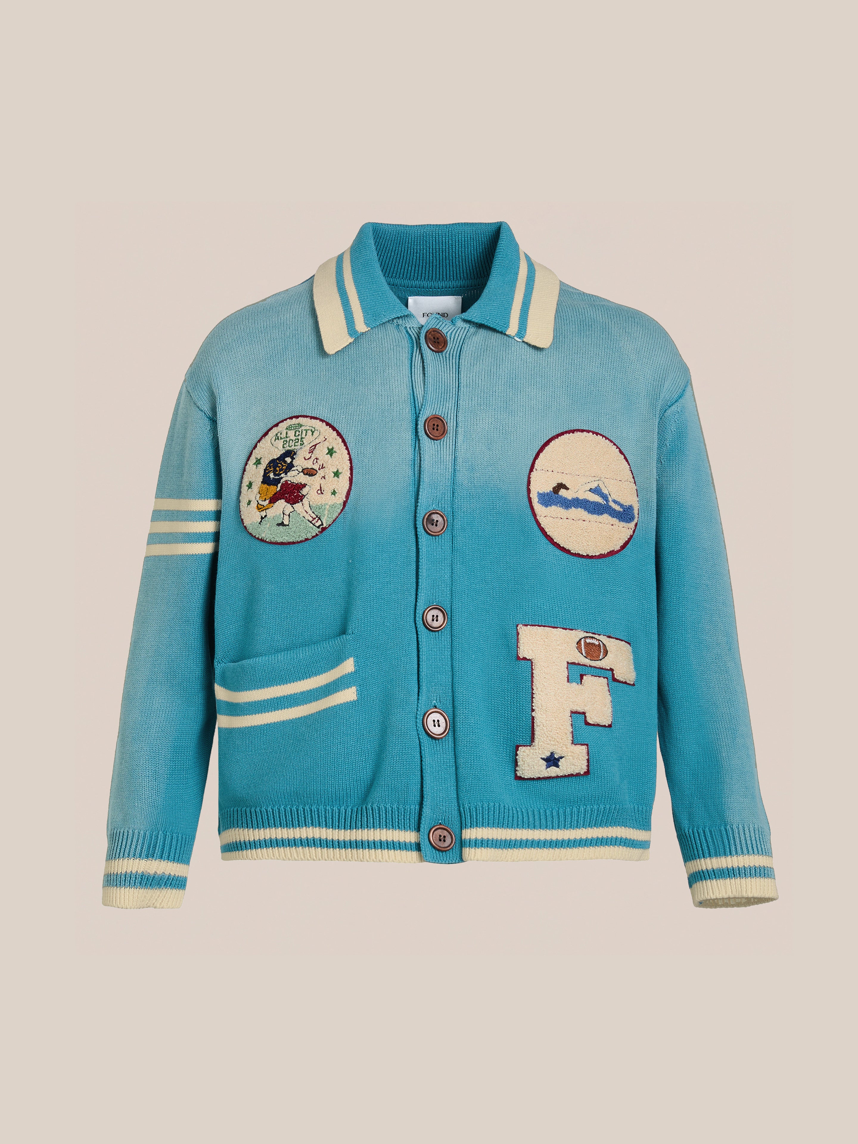 The FOUND Fin Varsity Patch Collared Cardigan is a vintage-inspired piece featuring white-striped sleeves, an "F" patch front, bird and landscape circular patches, brown buttons, and ribbed cuffs for a classic collegiate style.