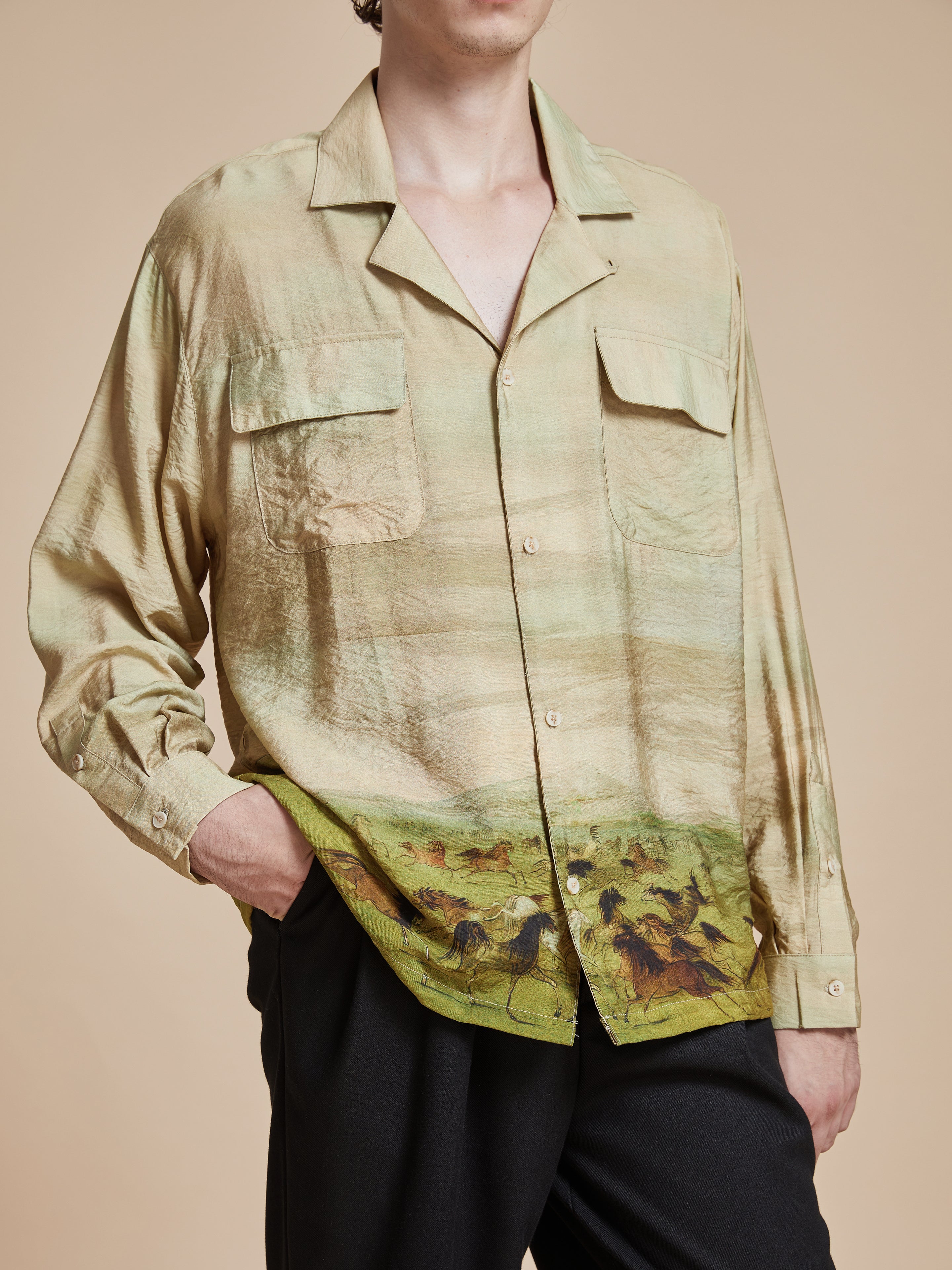 A man wearing a Found Grasslands Long Sleeve Camp Shirt, inspired by Phulkari motifs, with an image of horses on it.