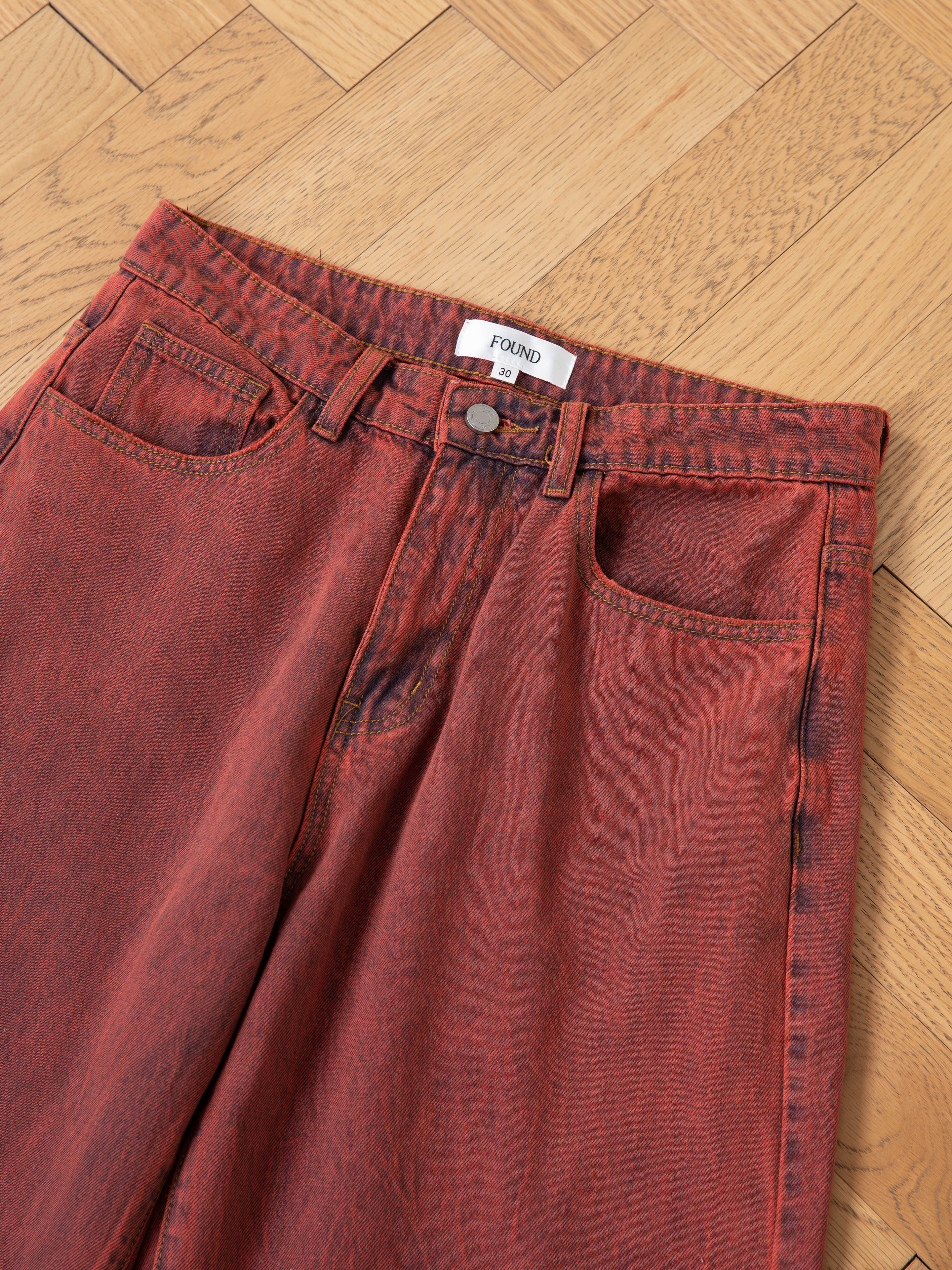 Lacy Baggy Jeans by FOUND, styled in vintage red wash denim, are displayed on a wooden floor featuring a "FOUND" label above the back right pocket.