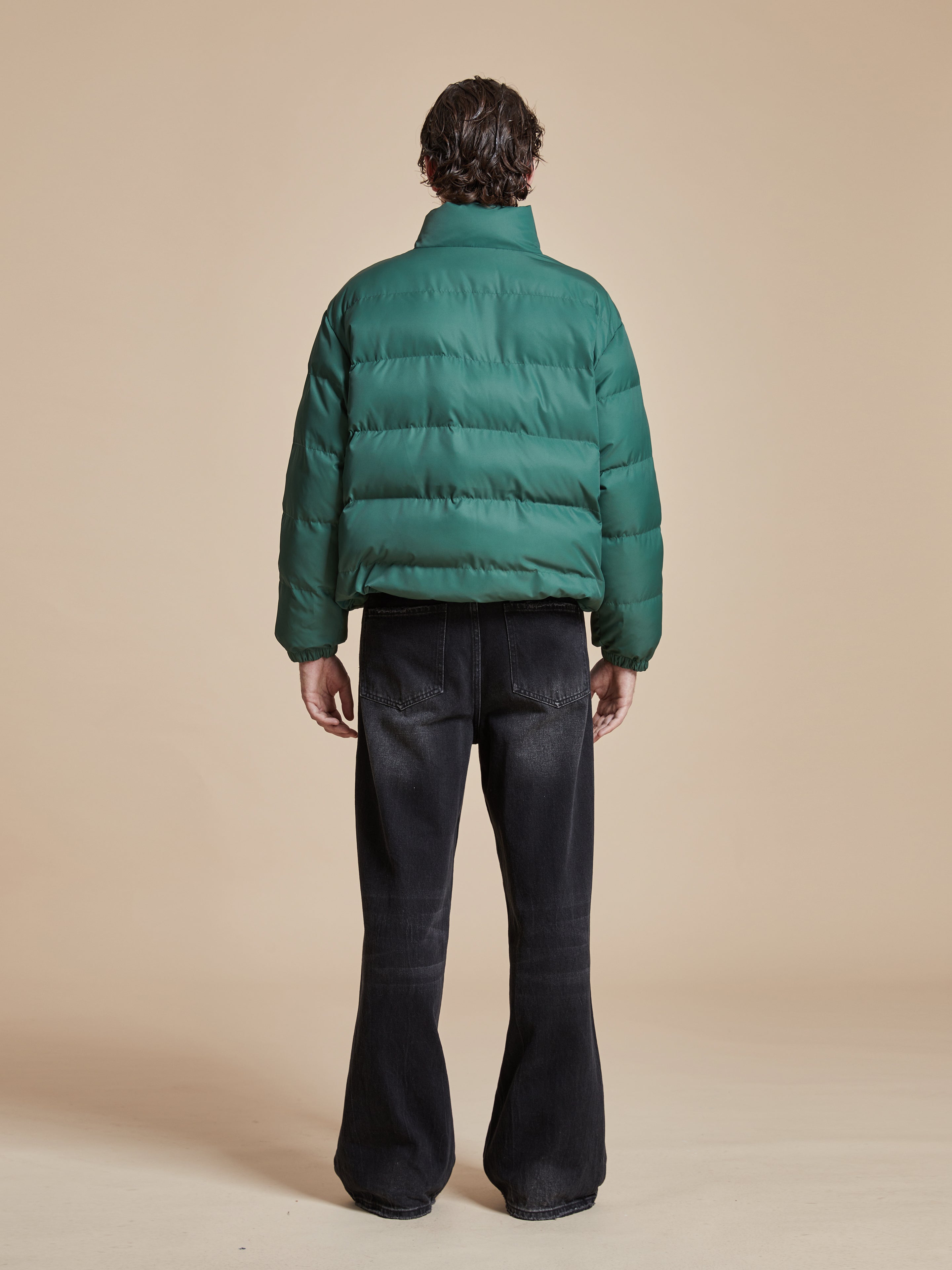 A man wearing a deep green Found Laurel Pine Puffer Jacket.