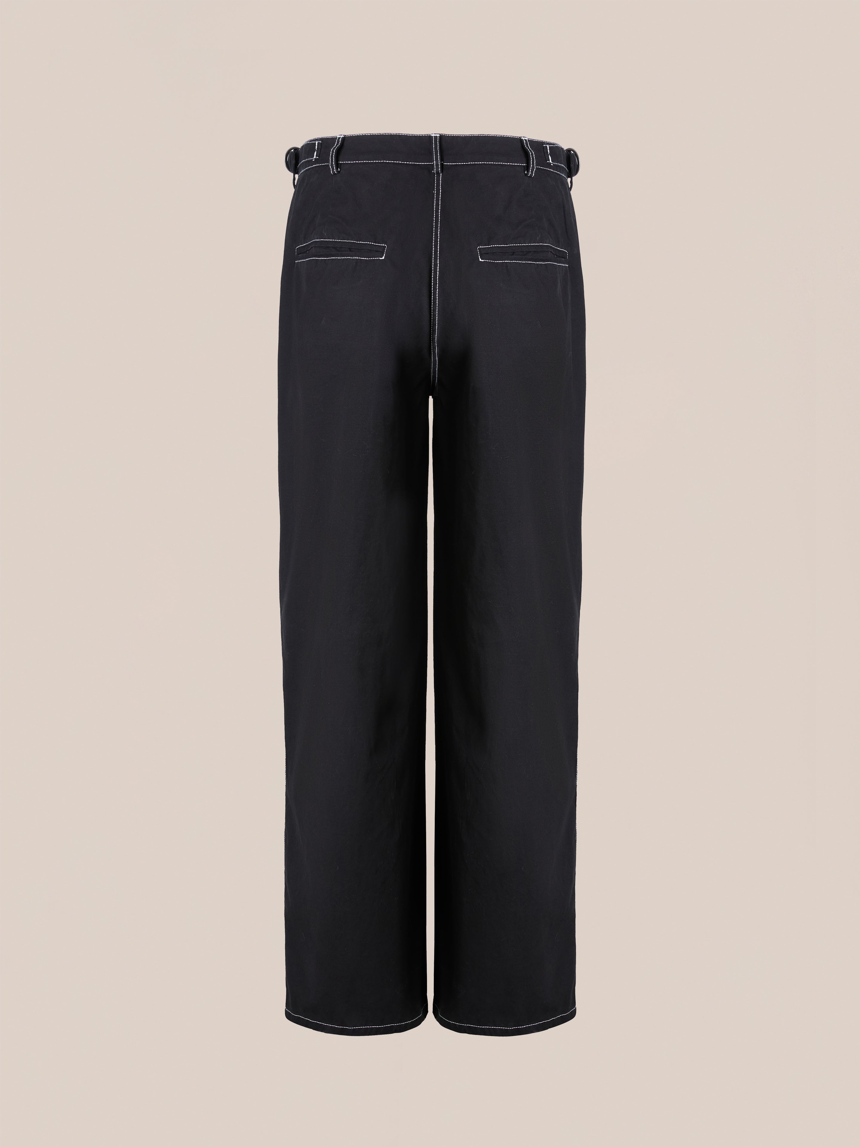 The Lucca Black Contrast Pocket Pants by FOUND are high-waisted black utility trousers featuring a relaxed straight-leg fit, white stitching, belt loops, and two back contrast pockets, showcased against a plain beige background.