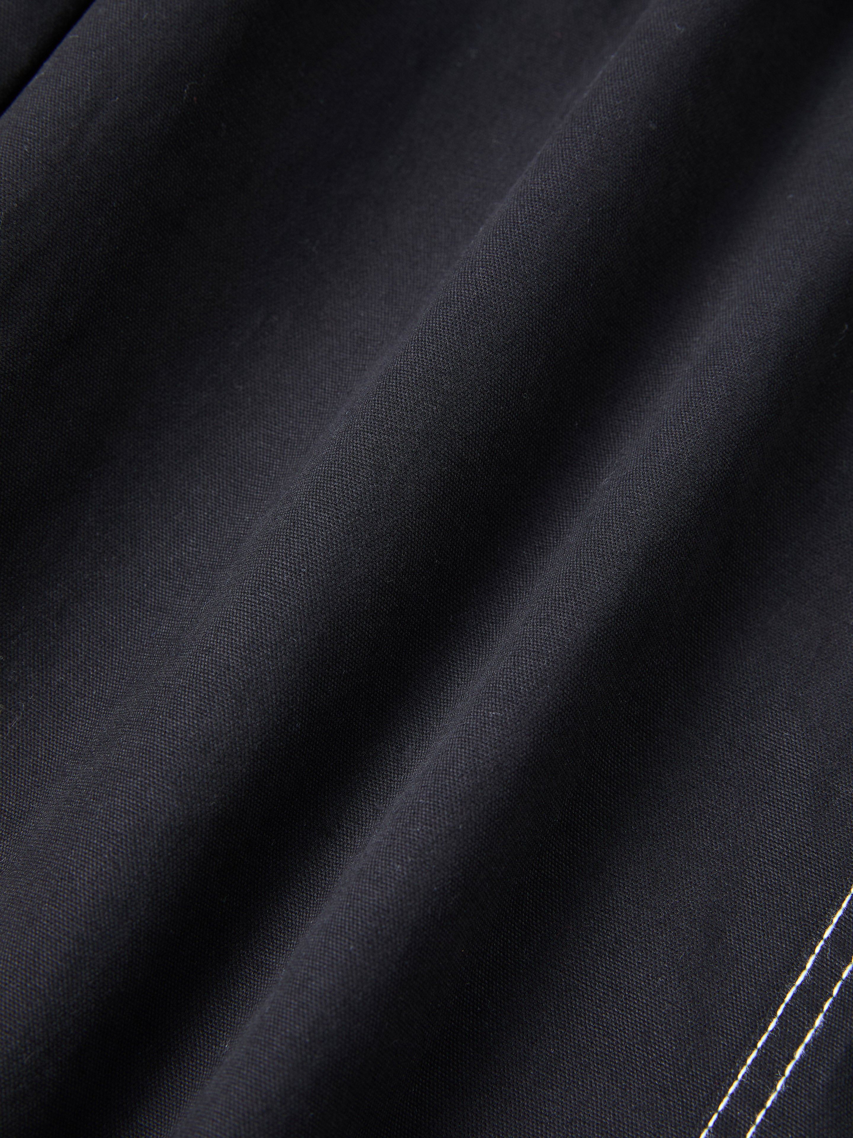 Close-up of the Lucca Black Contrast Pocket Pants by FOUND, featuring a relaxed straight-leg fit with dark fabric and parallel white stitching lines.