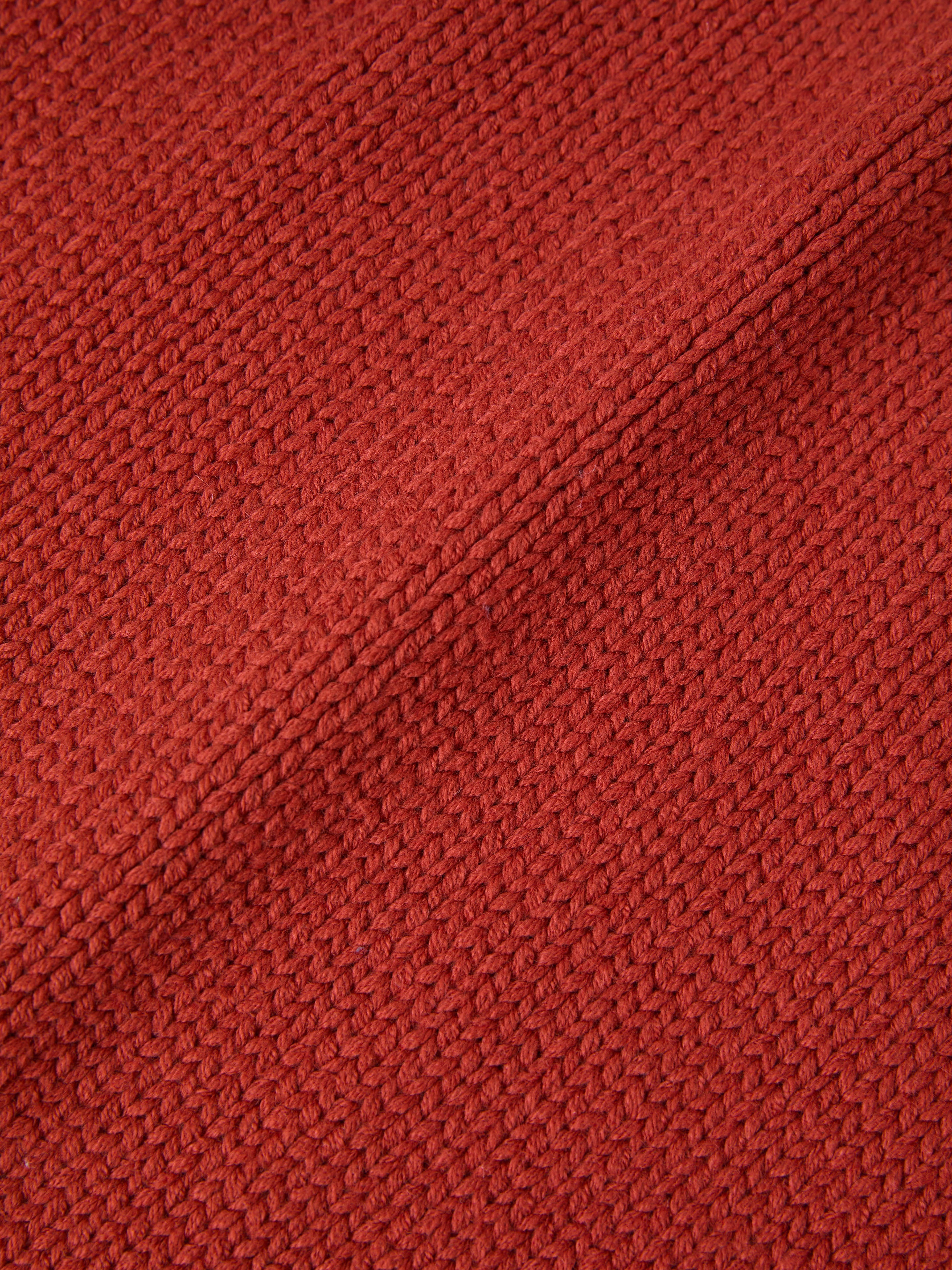 Close-up of the Hunter Knit Collared Cardigan by FOUND, showcasing a heavy knit cotton fabric with a red textured finish and a charming diagonal seam.