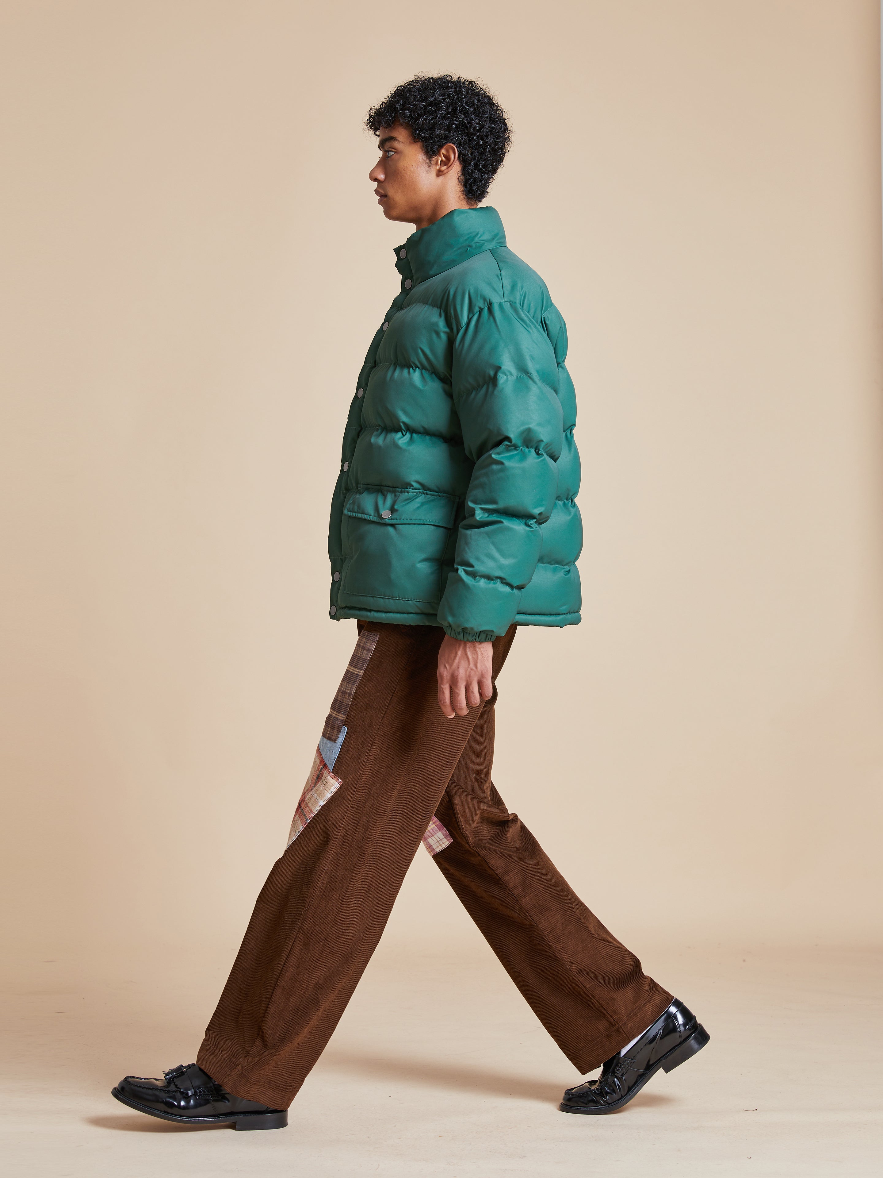 A man wearing a deep green Found Laurel Pine Puffer Jacket.