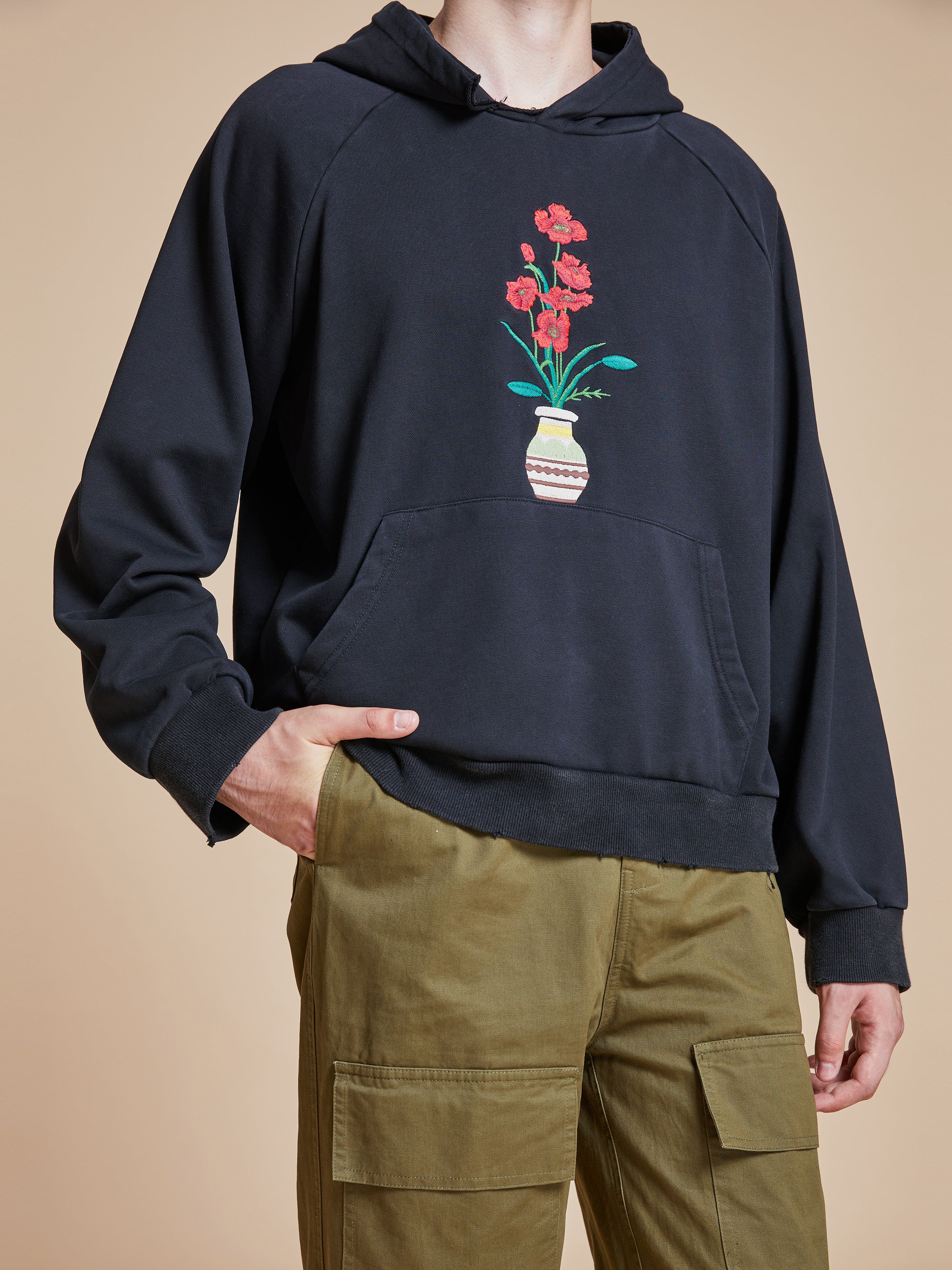 A man wearing a black Found Flowers Vase Hoodie.