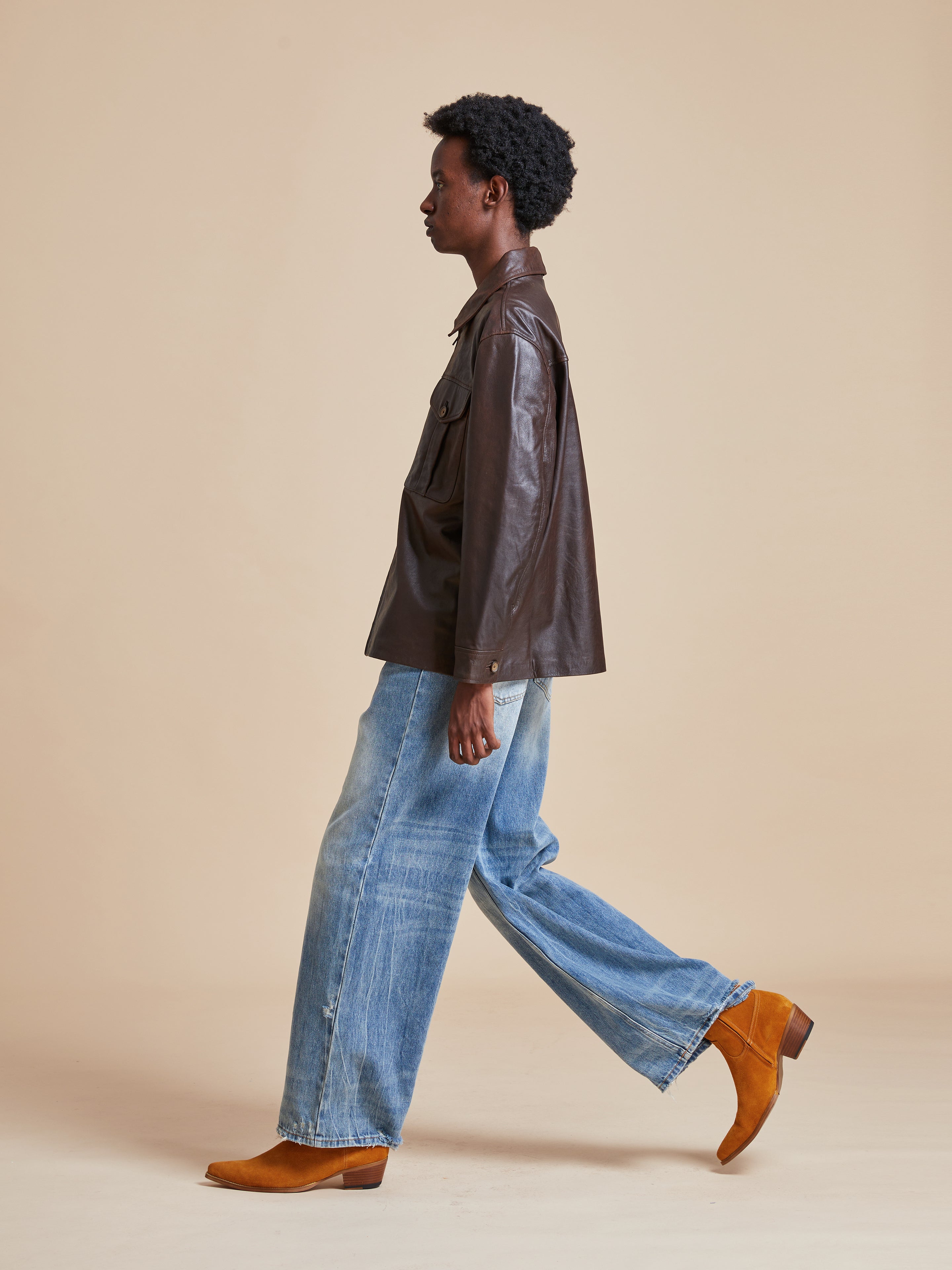 A woman wearing a Found Sepia Leather Overshirt and wide leg jeans.