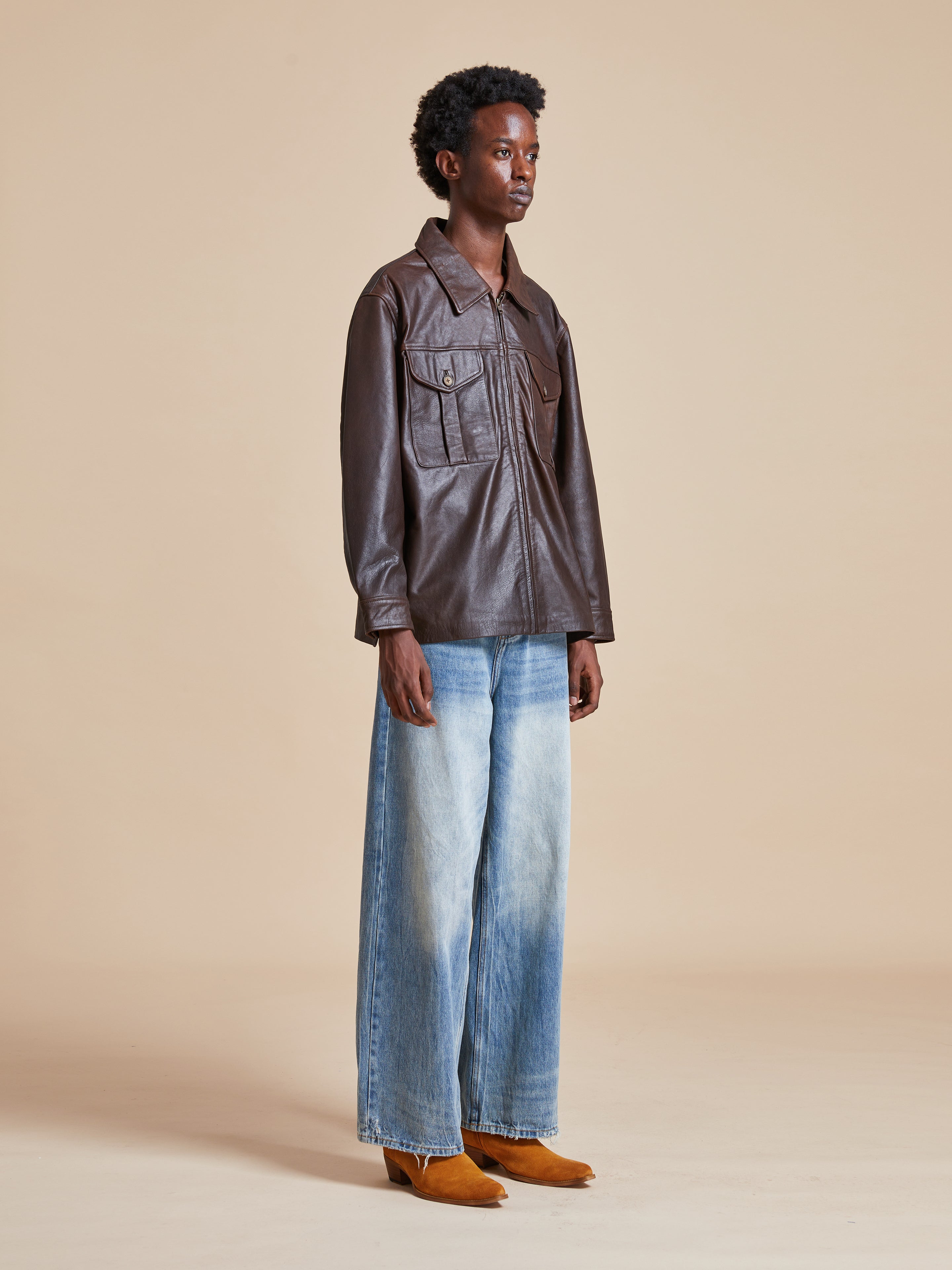 A man wearing a Found Sepia Leather Overshirt and blue jeans.