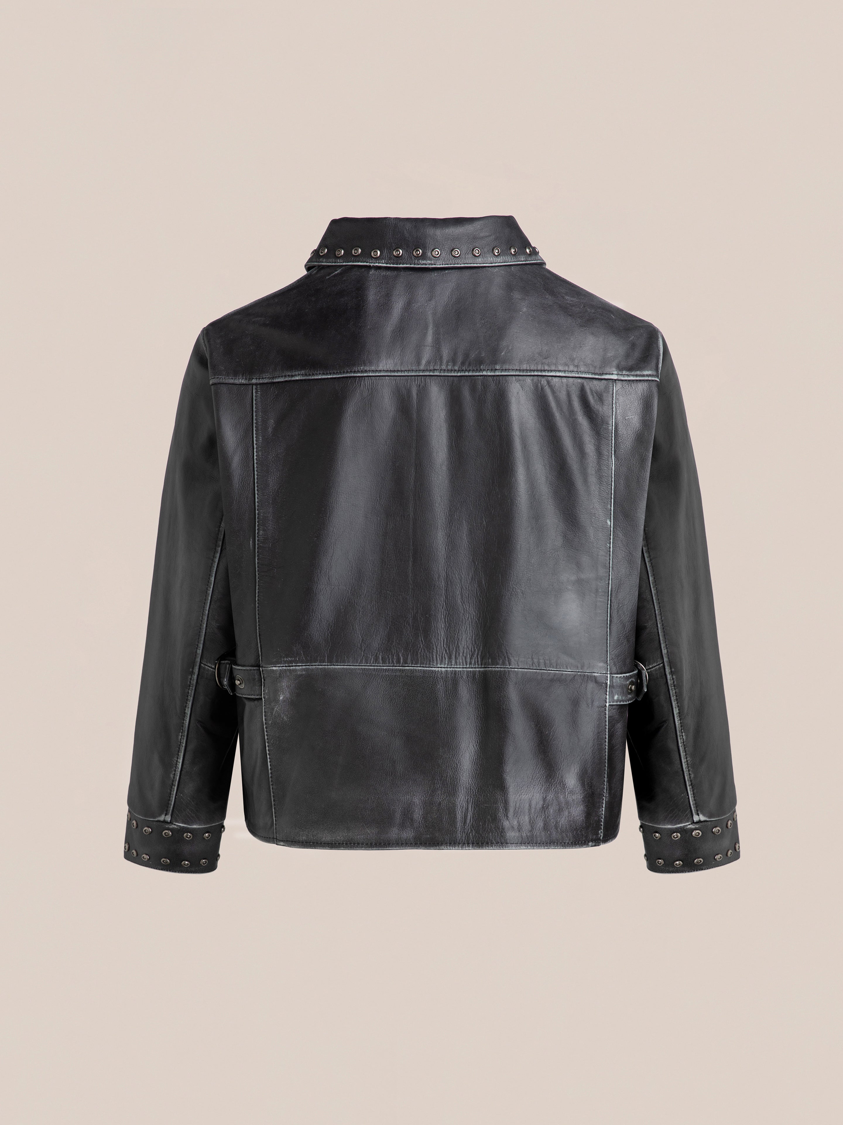 The Studded Leather Pocket Jacket by FOUND is shown from the back, highlighting its studded collar and cuffs against a plain beige background.