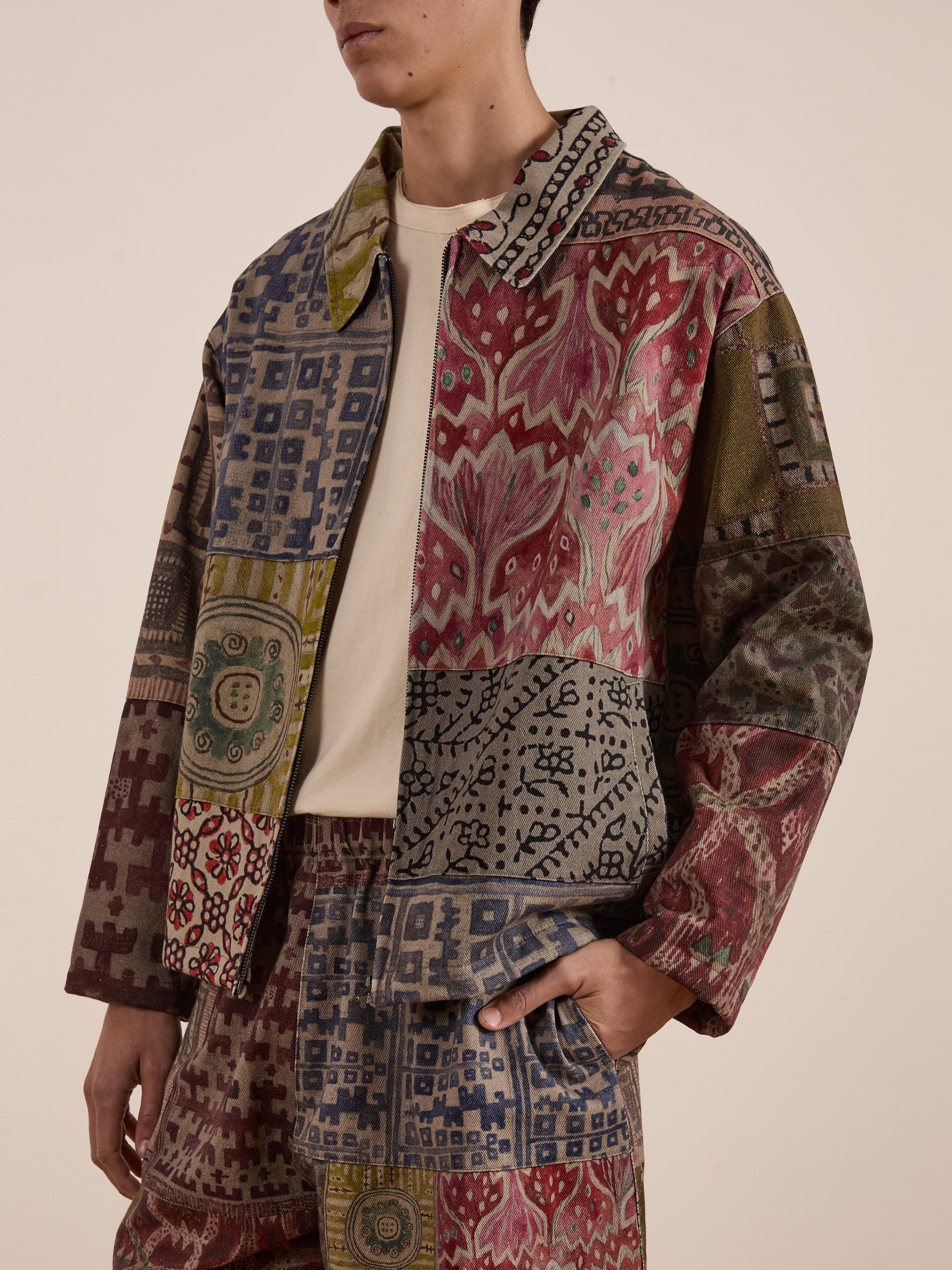 Wearing the FOUND Watercolor Mosaic Work Jacket and matching pants, the person stands confidently with one hand in their pocket against a plain background.