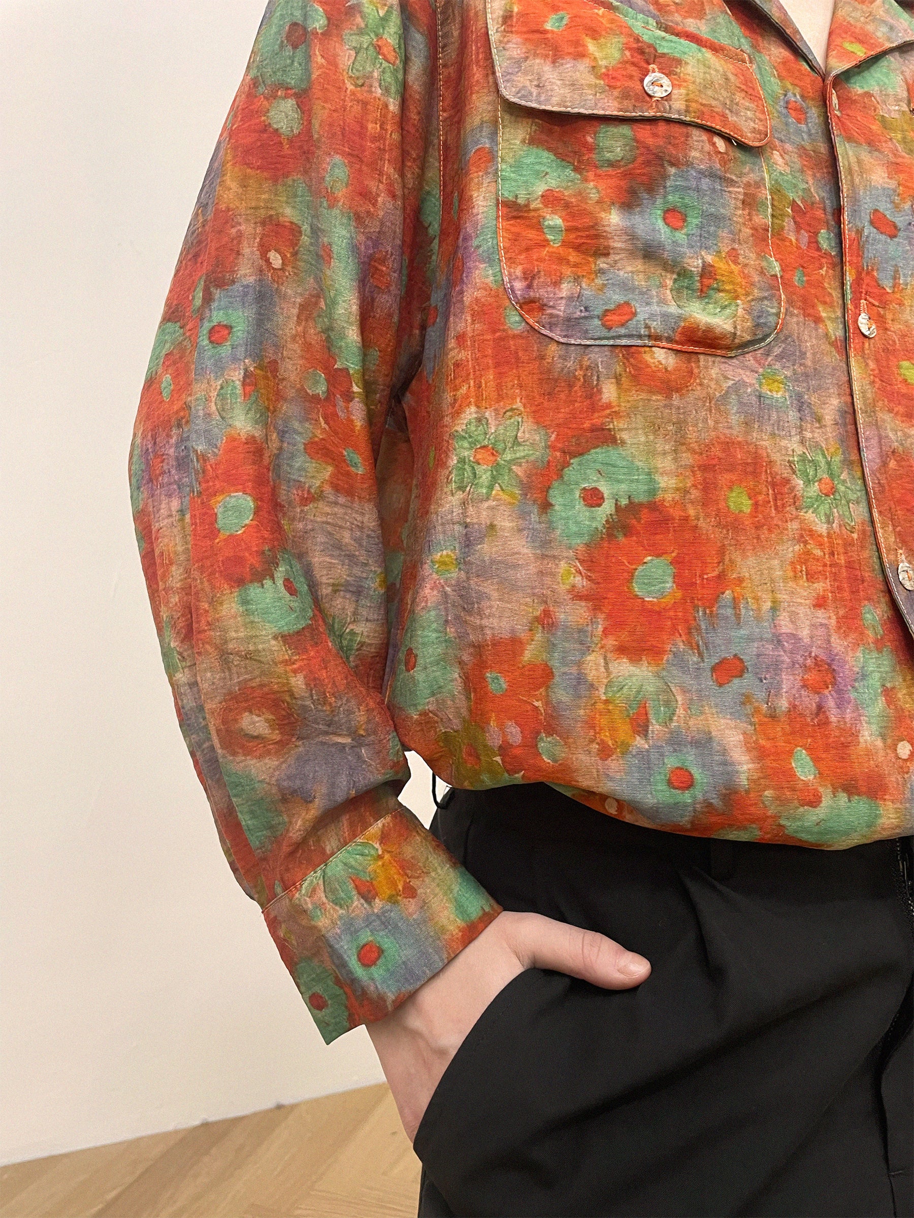 A person wears a Found Waterblend LS Camp Shirt with a colorful floral pattern, featuring dual chest pockets, and has their hand in the pocket of black Elbas Cargo Pants.