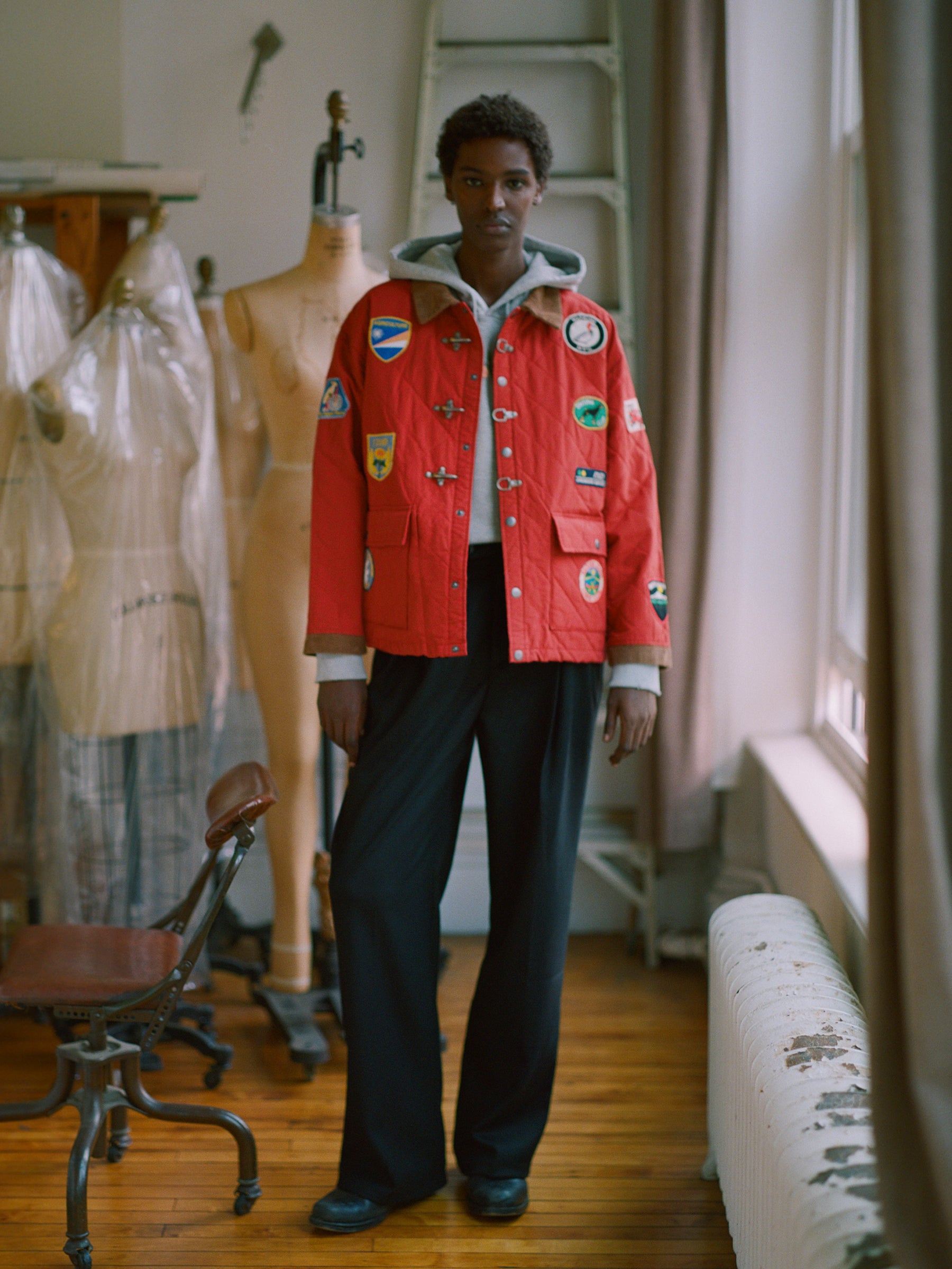 A woman in a Found Farmstead Quilt Patch Jacket standing in a room surrounded by mannequins.