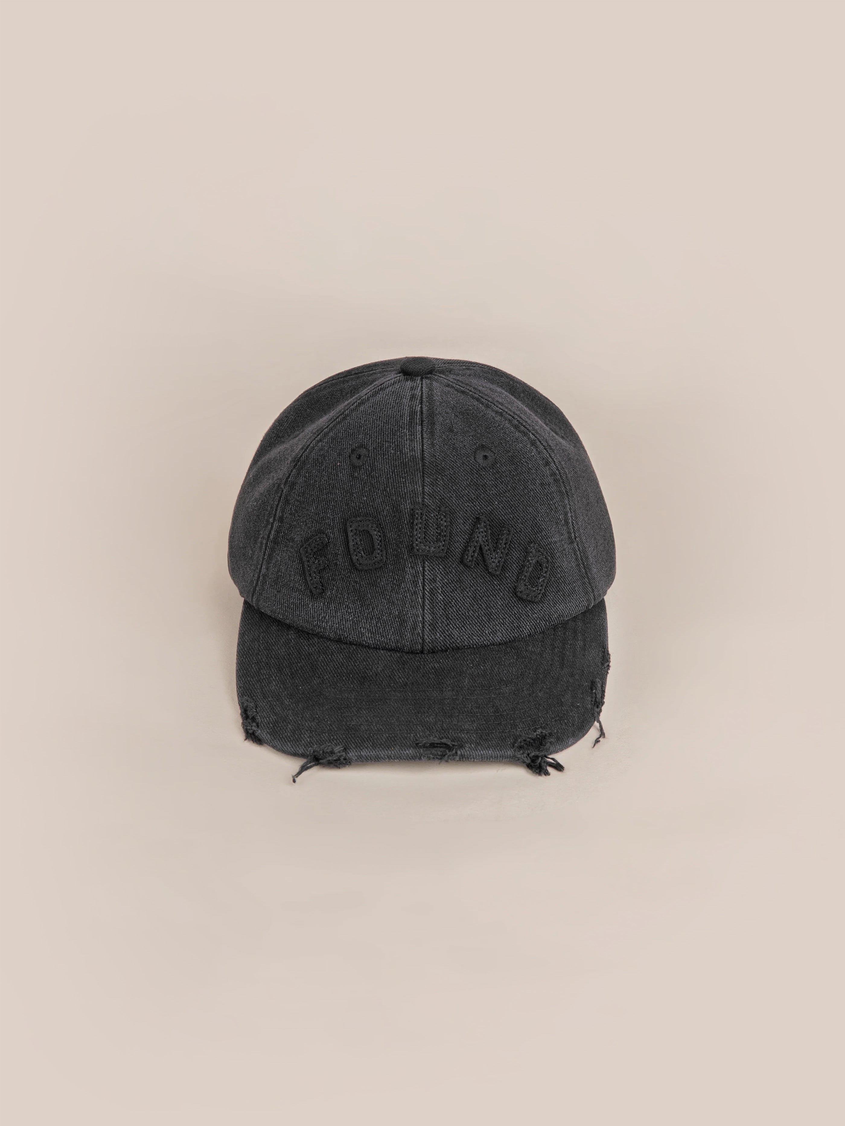 The Black Felt Patch Cap by FOUND features "FOUND" embroidered on the front and is made from vintage washed fabric for a faded, distressed appearance.