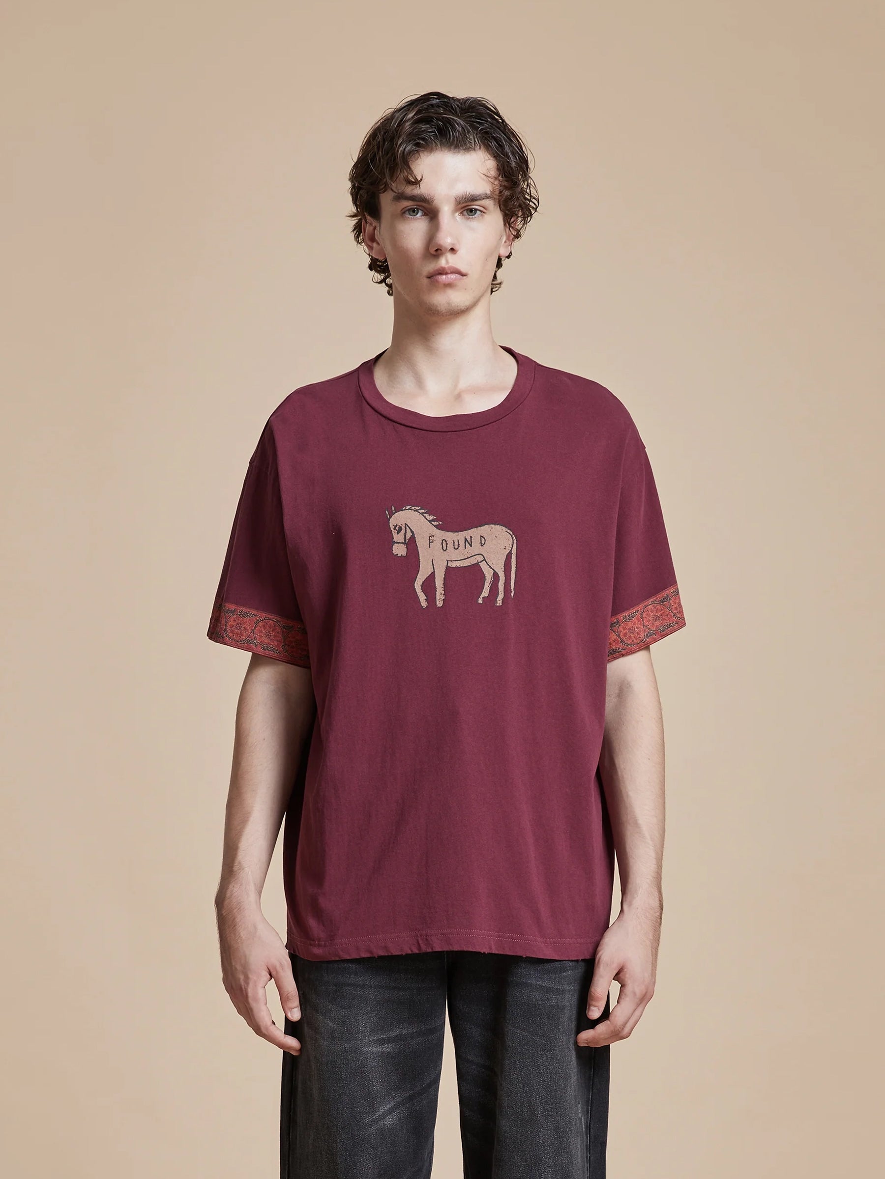 A man wearing a Found Horse Embellishment Tee in burgundy.