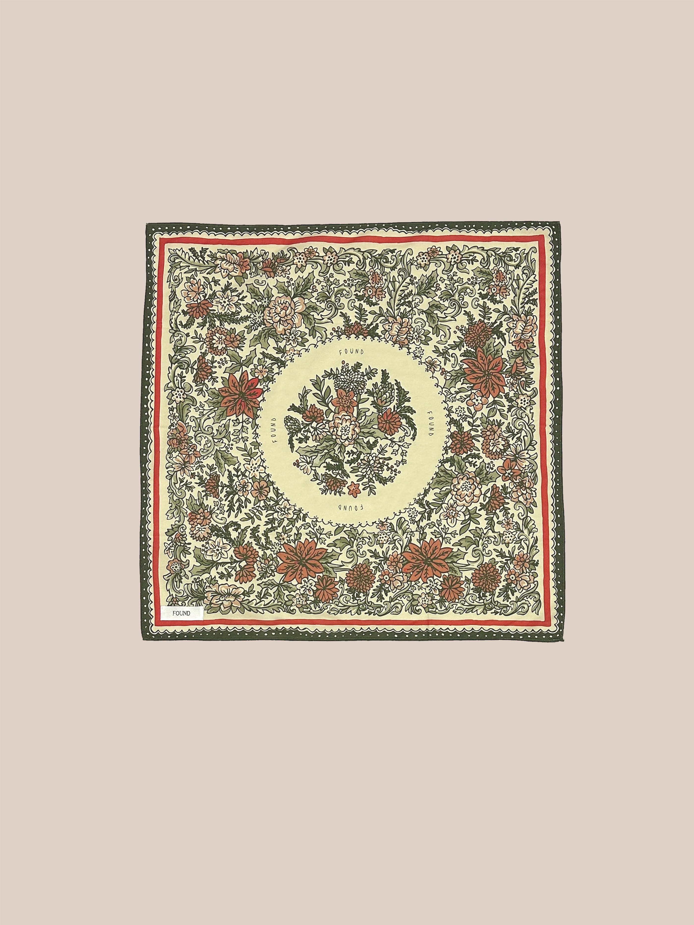 This product is the Floral Garden Bandana by Found, characterized by a square textile adorned with intricate floral patterns inspired by Phulkari artwork from the Punjab region. It features red, green, and beige hues set against a light background, centered around an oval design framed by a decorative border.