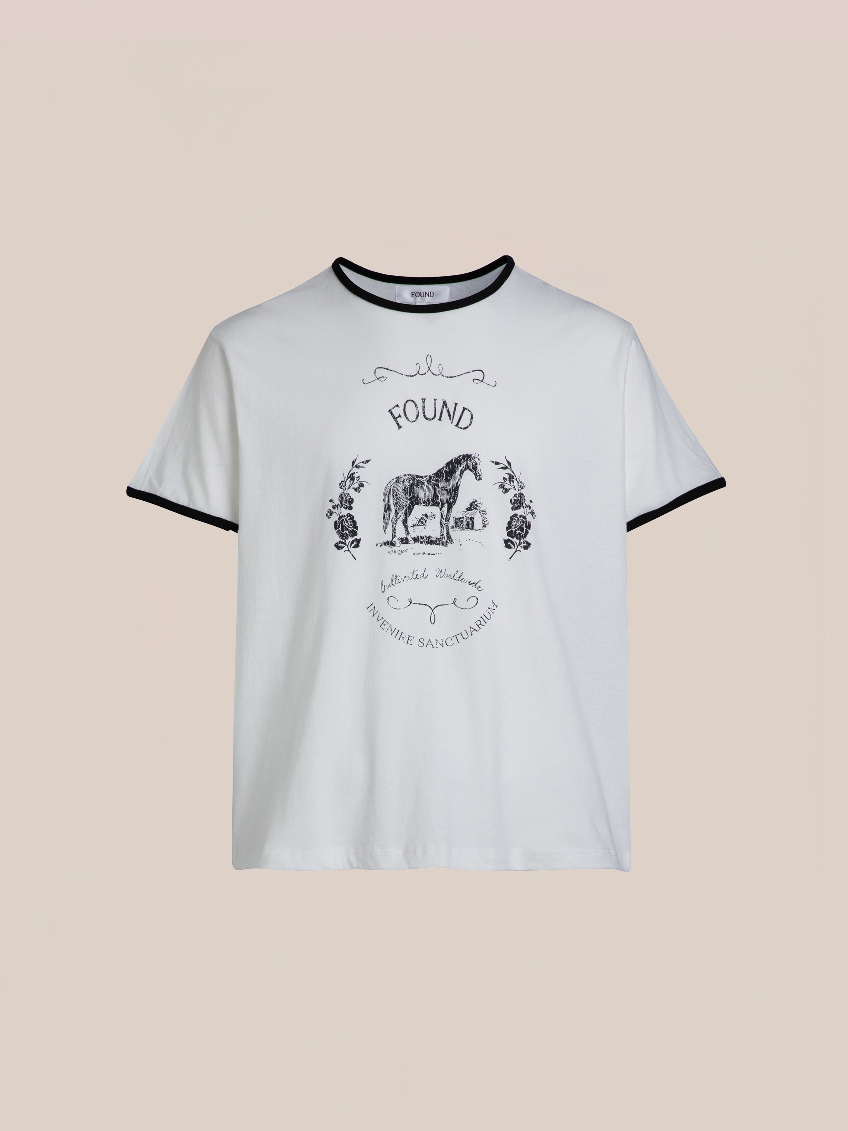 Horse Crest Ringer Tee by FOUND featuring a white base with black trim and an illustration of a donkey adorned with floral elements. The design includes the text "FOUND," "The Gentle Barn," and the tagline "Teaching People Kindness and Compassion to Animals, Each Other, and Our Planet.