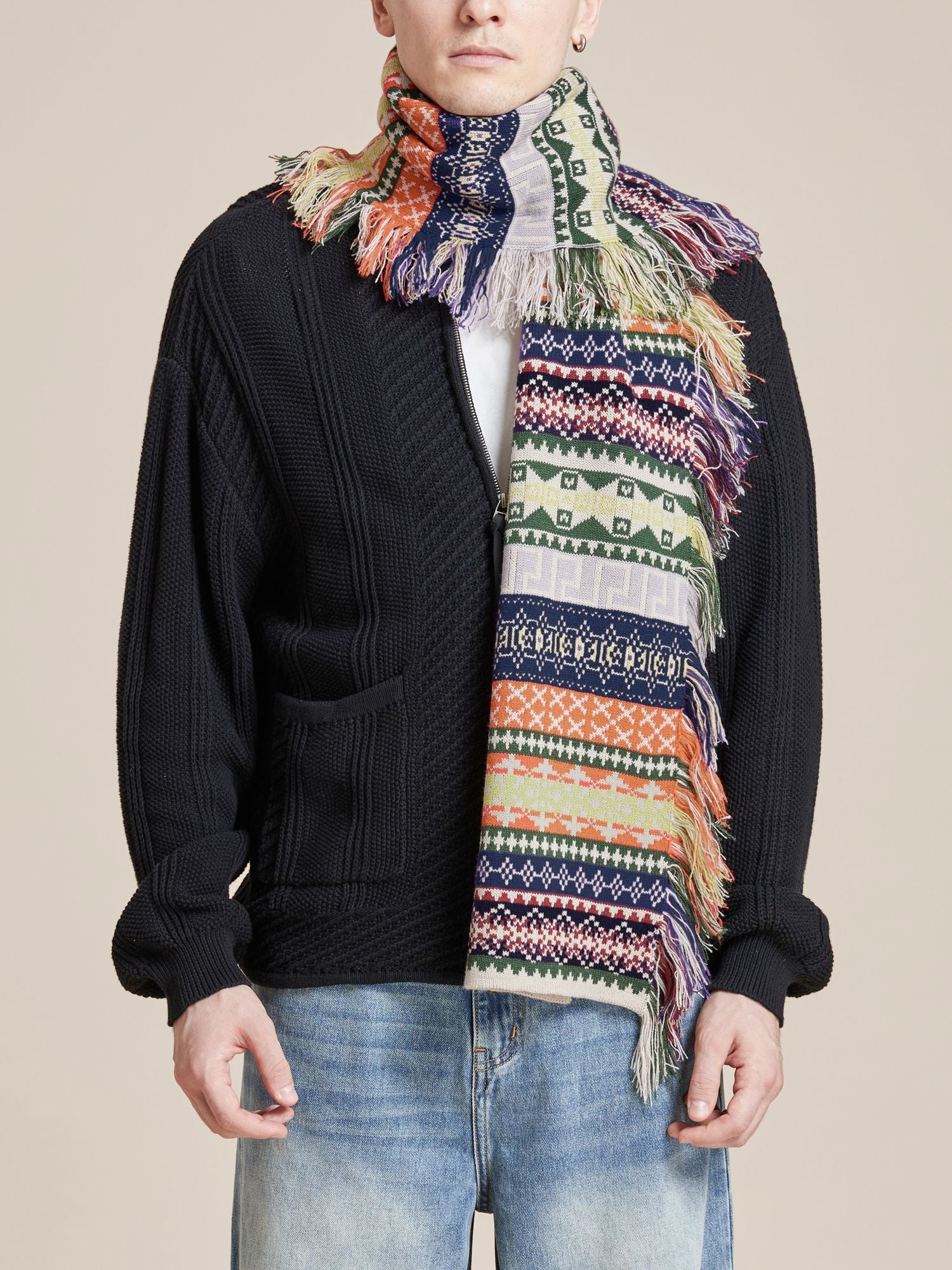 A person wearing a black sweater, blue jeans, and a Found Isles Scarf with hand-distressed tassels and colorful patterns.