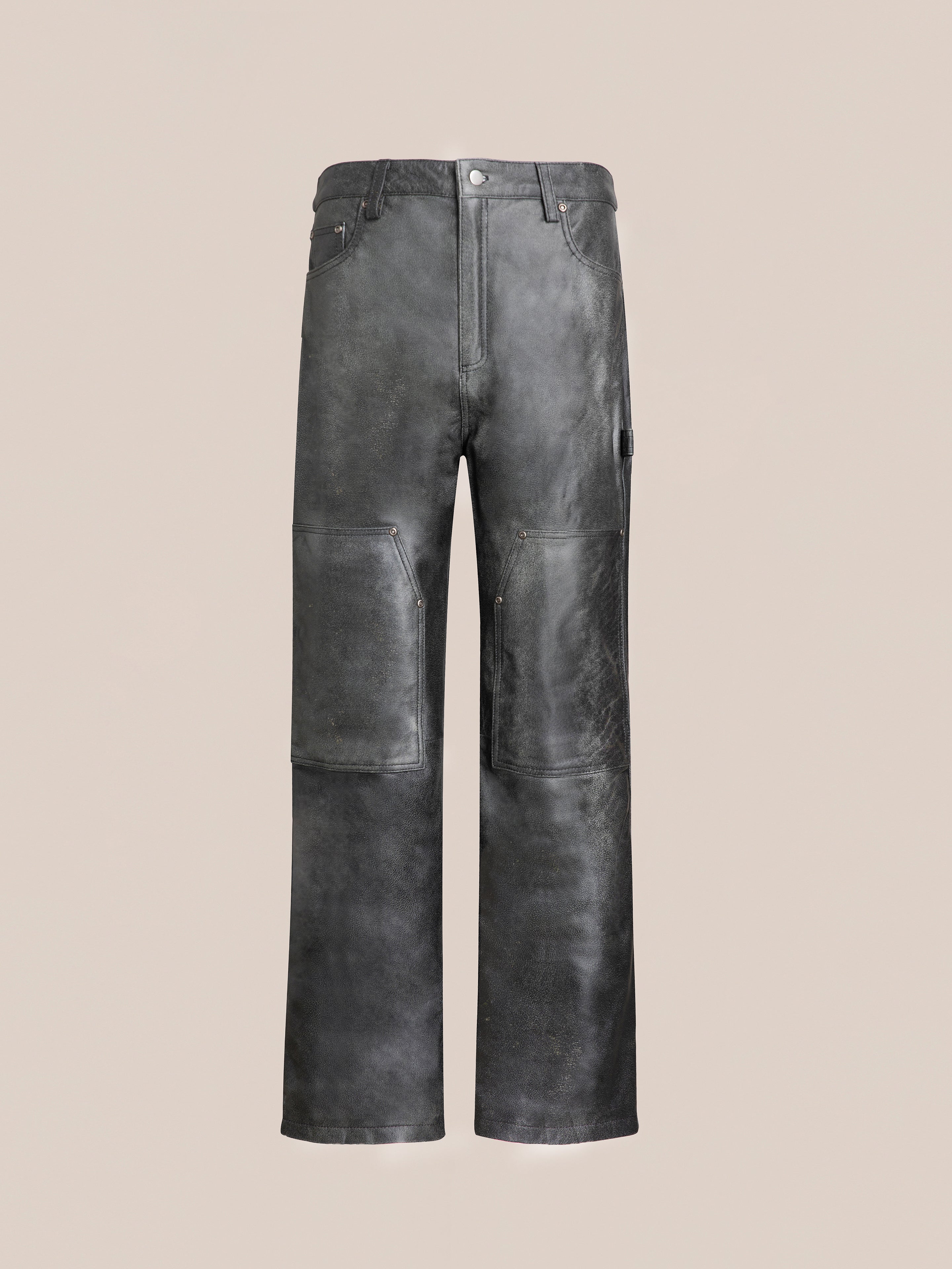 Introducing the Distressed Genuine Leather Carpenter Pants by FOUND. These black leather pants showcase visible seams, front pockets, and a button-zip closure. They feature a rugged, worn texture with an authentic double-knee silhouette and are crafted from ethically sourced materials.