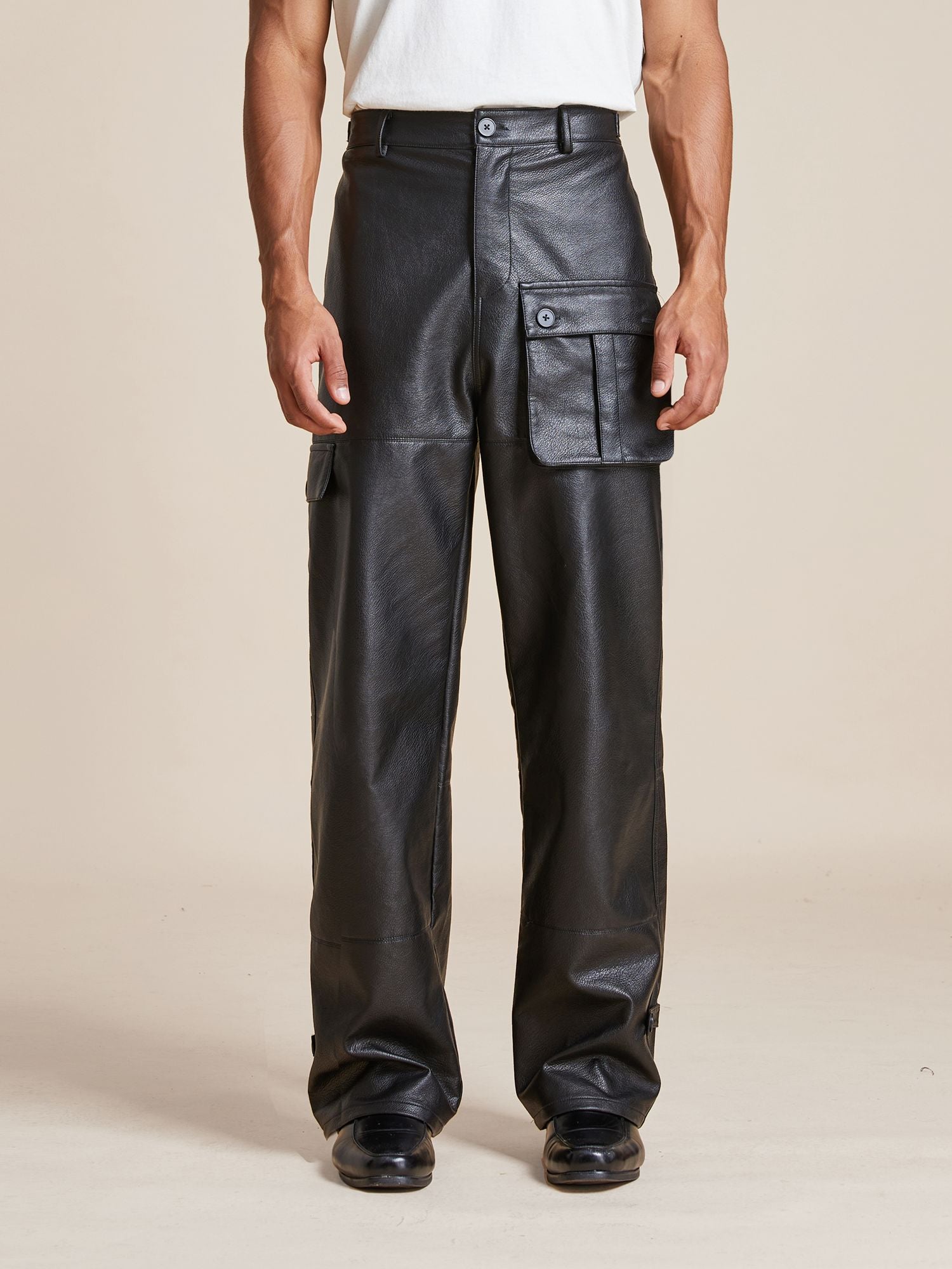 Person in Found Faux Leather Cargo Pants with a white shirt, standing against a plain background.