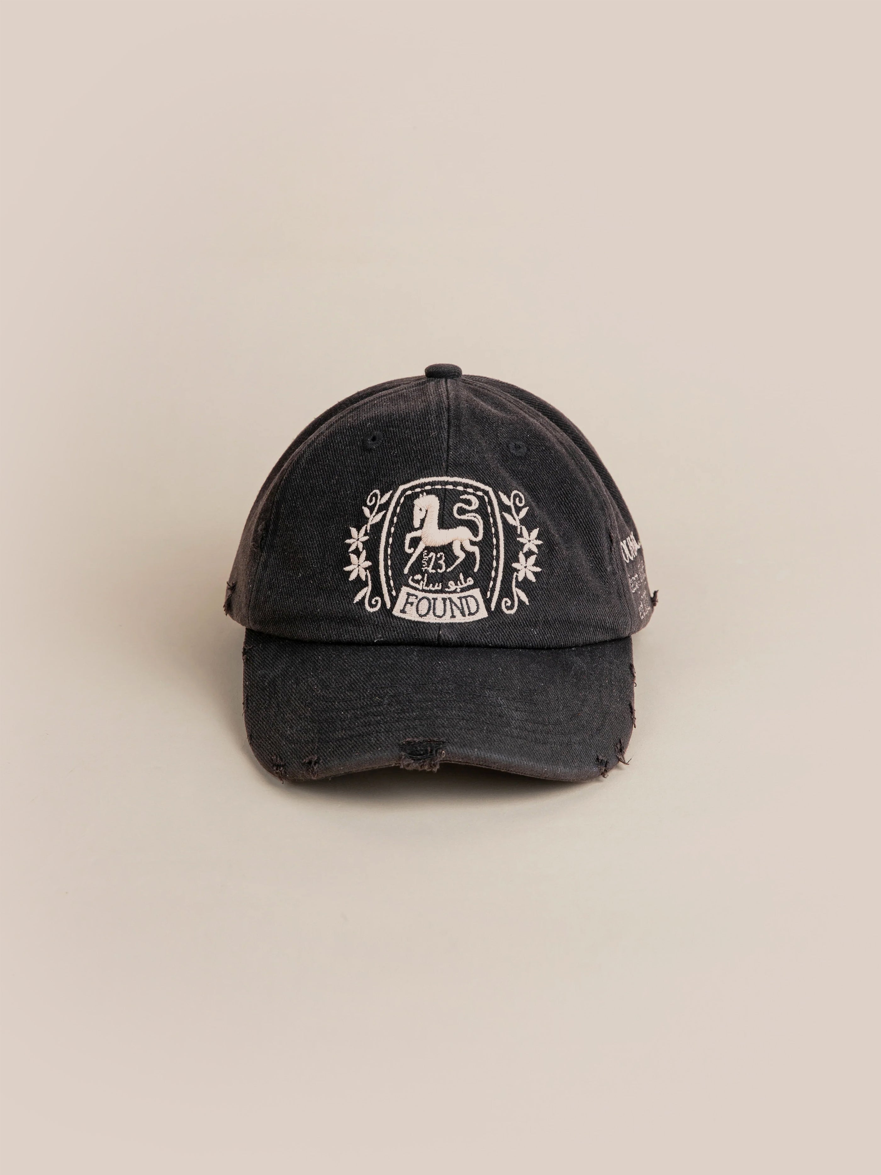 The Logo Crest Cap by FOUND is a black baseball cap featuring a vintage-style emblem with a lion and the number '23'. The word "FOUND" is displayed beneath the lion on the front. Its slightly worn look gives it an authentic charm.