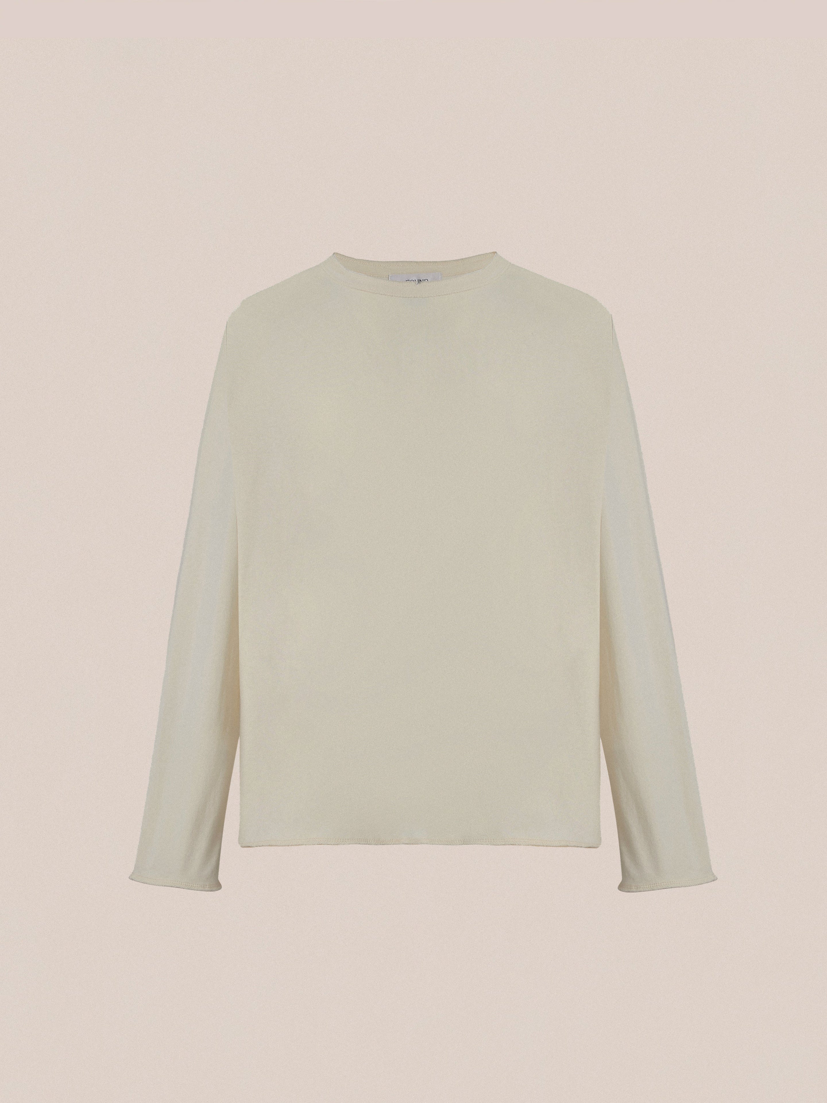 A plain, long-sleeved off-white Reversed LS Tee by Profound, showcased on a beige background and crafted with premium materials for a timeless look.