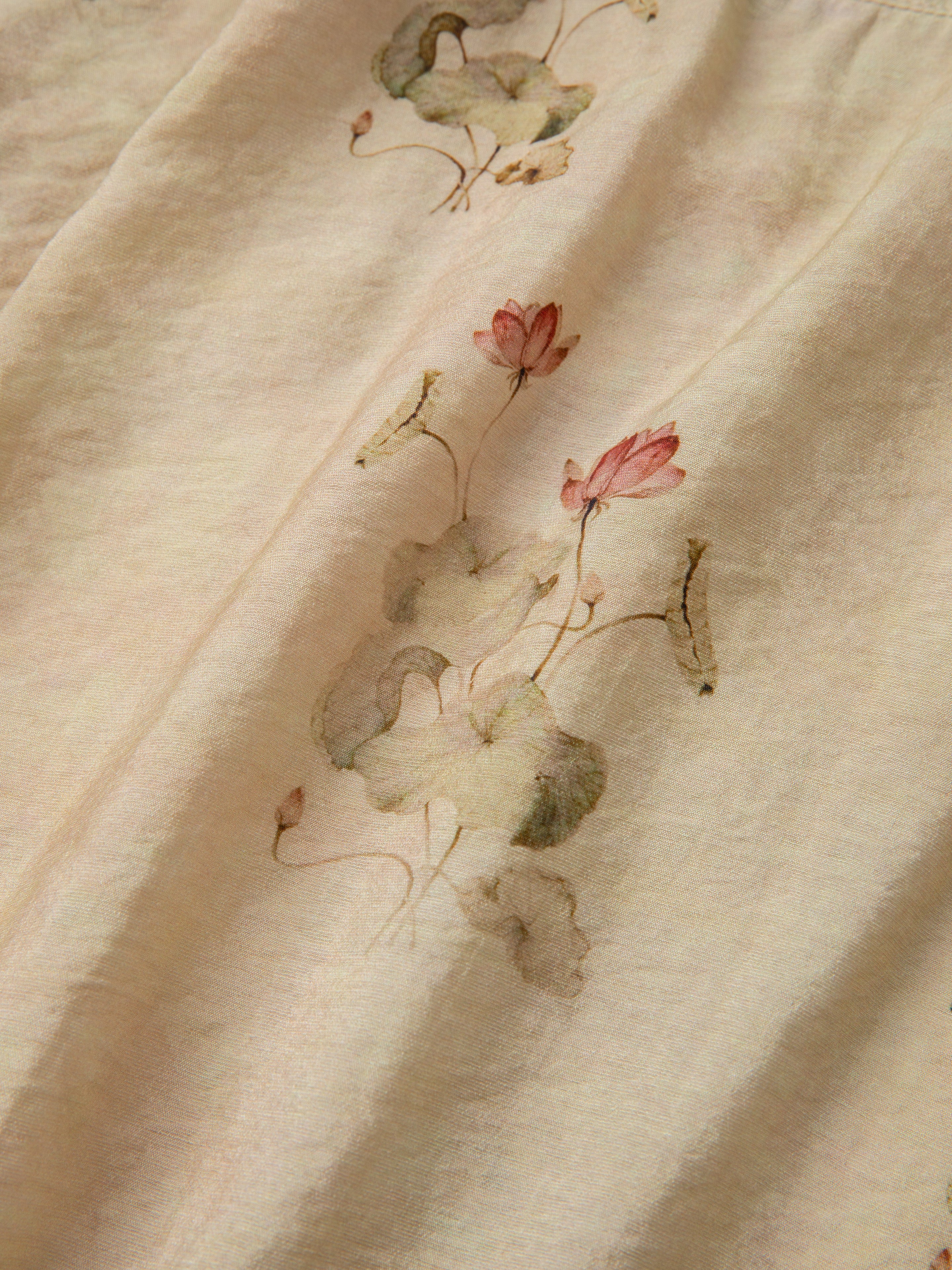 Close-up of a light fabric with a delicate floral pattern featuring pink and white flowers with green leaves, reminiscent of the timeless silhouette seen in the Lotus LS Camp Shirt by Found.