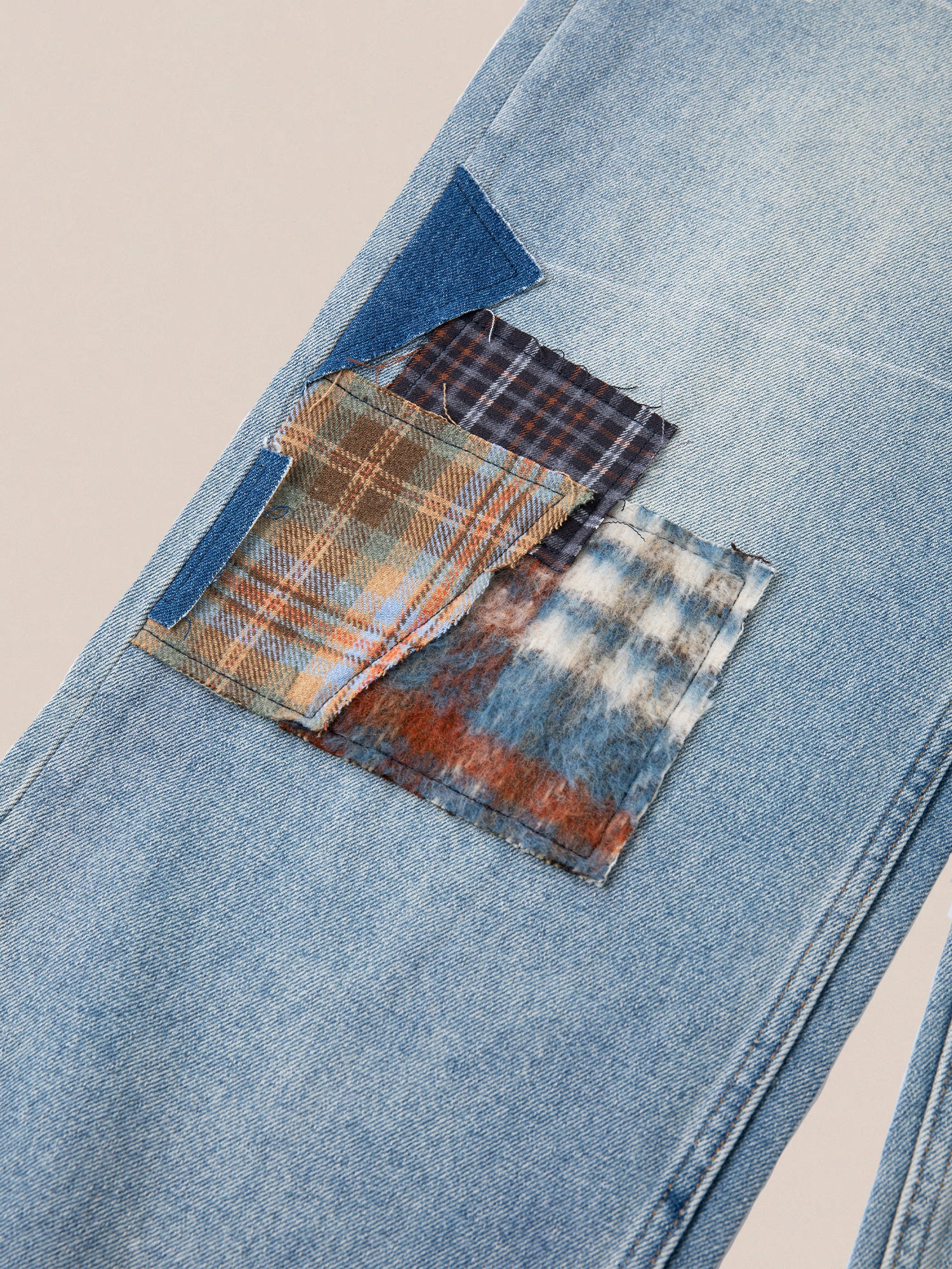 The Mix Patch Jeans by Profound feature light blue denim fabric with vibrant patchwork, incorporating plaid and checkered patterns in shades of blue, orange, and brown. These vintage-inspired jeans offer a distressed look that adds a unique flair to the classic denim cotton design.