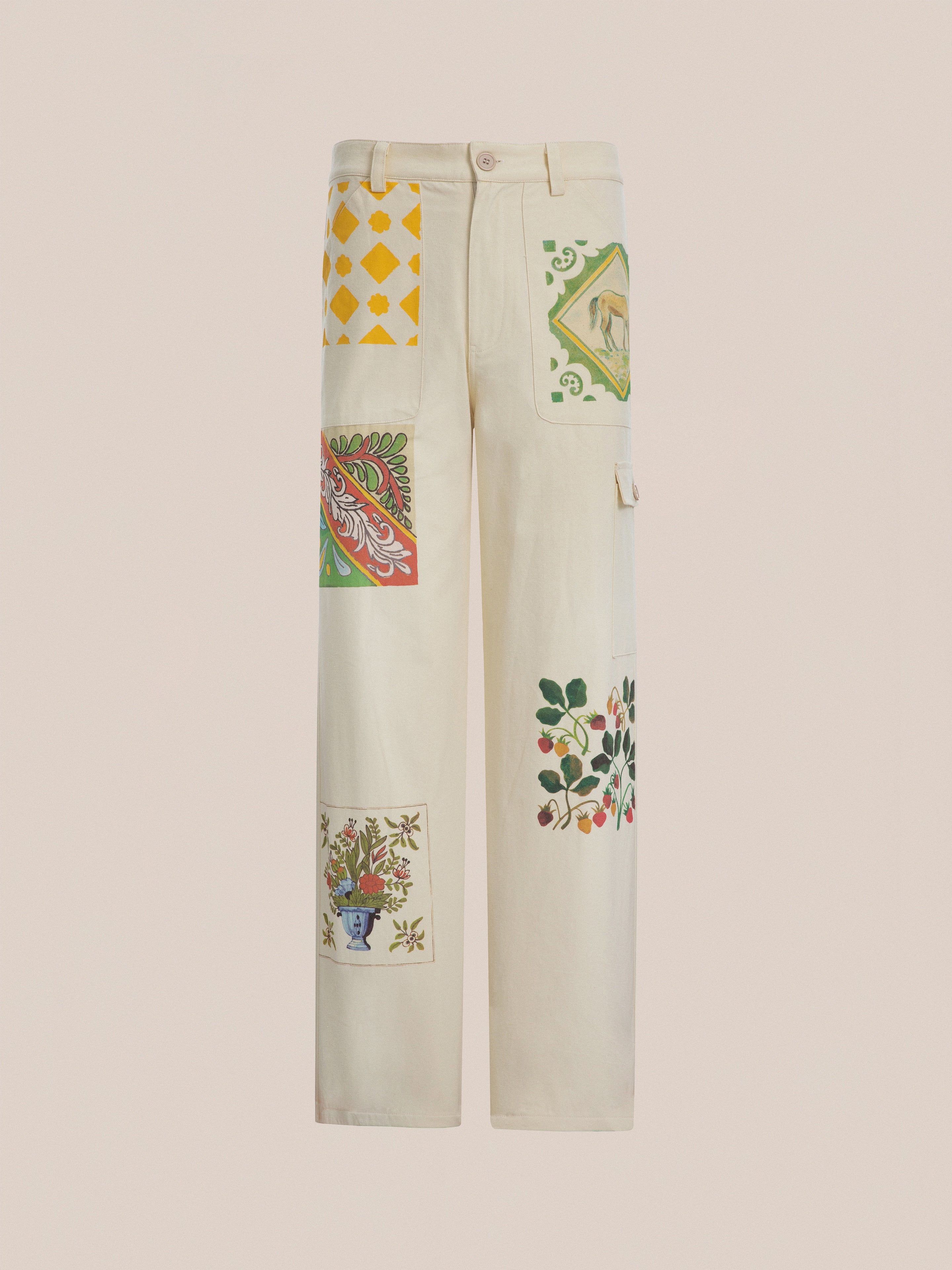 Profound's Mosaic Pants in cream-colored cotton canvas fabric with colorful patchwork designs, featuring yellow diamonds, floral patterns, and a vase, reminiscent of Indo-Aryan patterns. These Mosaic Pants effortlessly combine tradition and modern style.