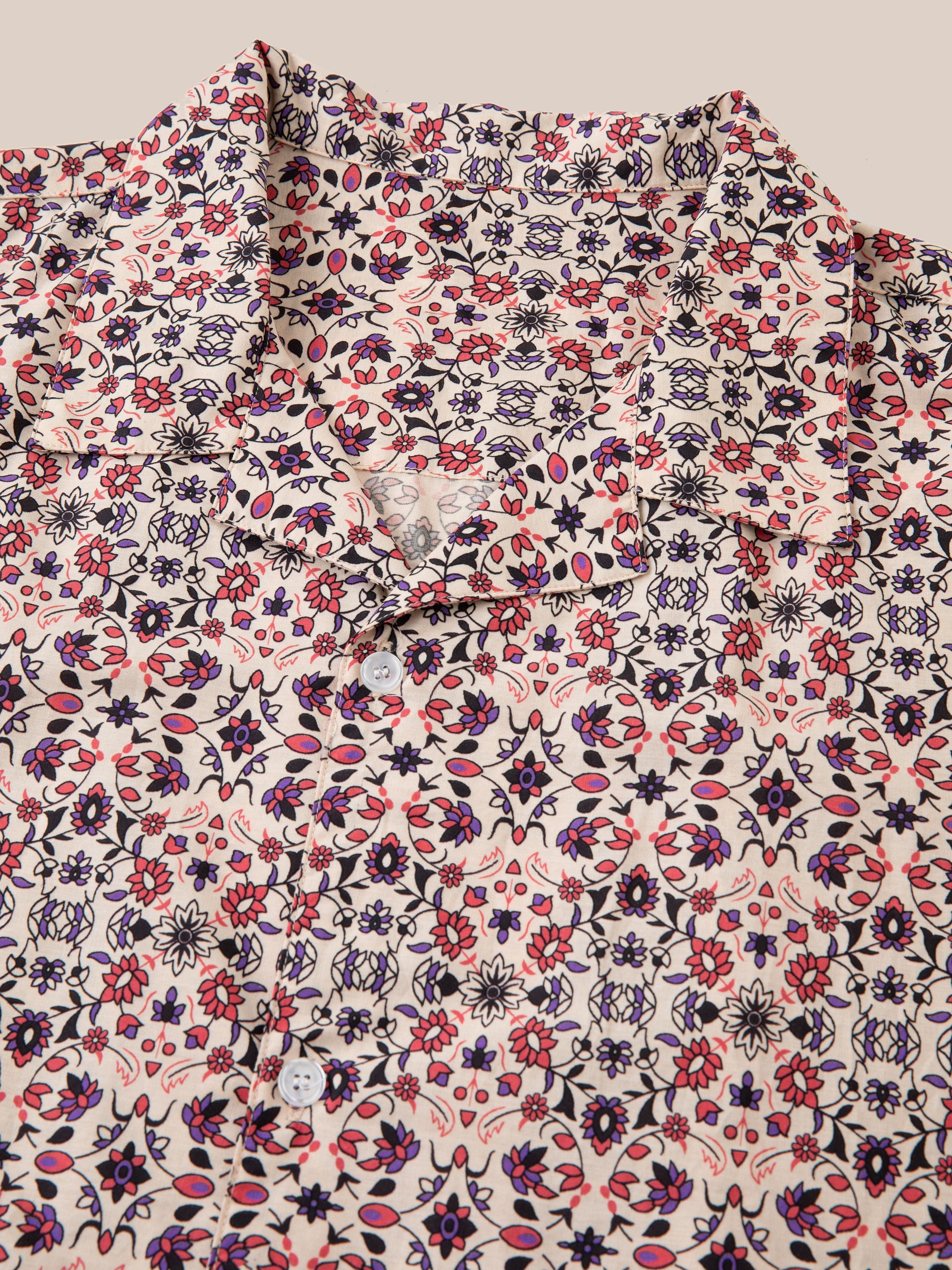 Close-up of a collared Profound Mughal Camp Shirt showcasing a detailed, multi-colored floral pattern in shades of red, blue, and pink against a white background. Made from 100% cotton fabric.