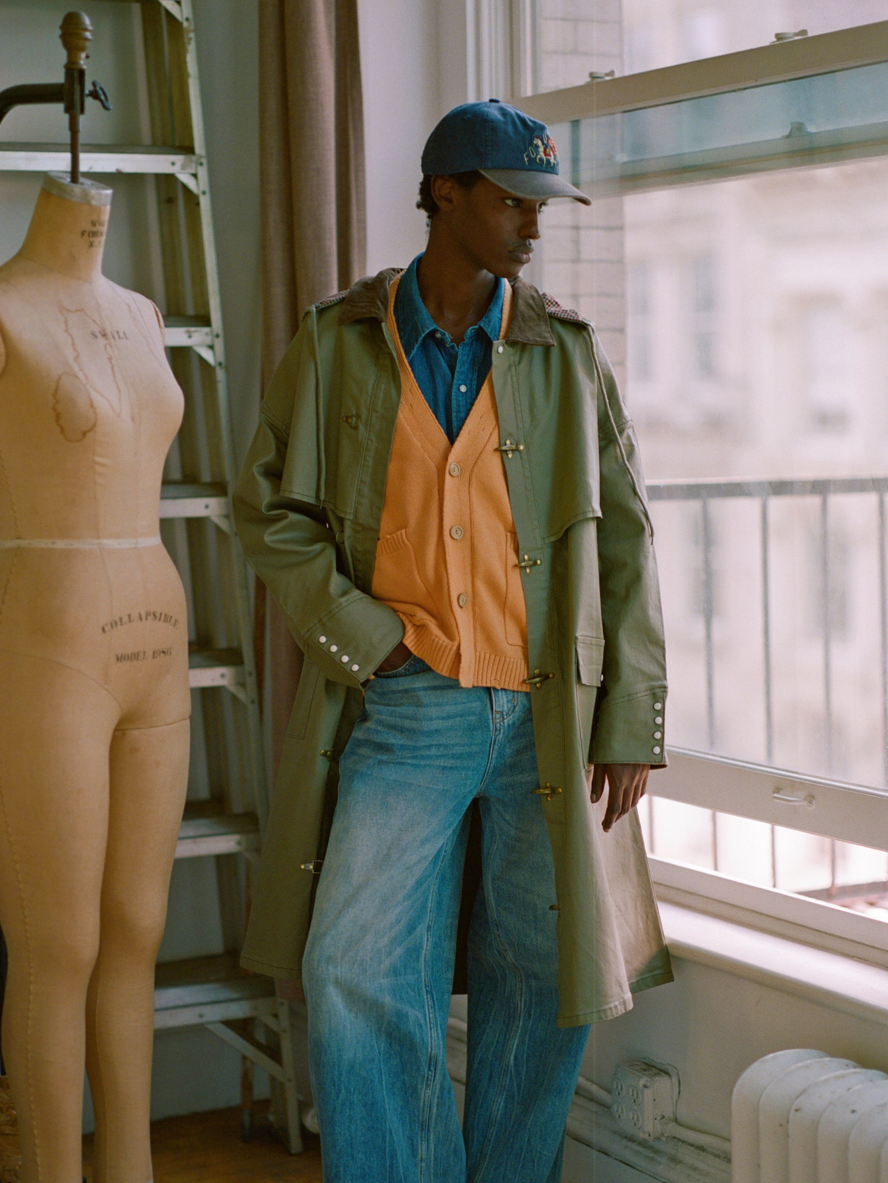 A man in a waxed cotton trench coat standing next to a mannequin dressed in a Found Prairie Buckle Coat.