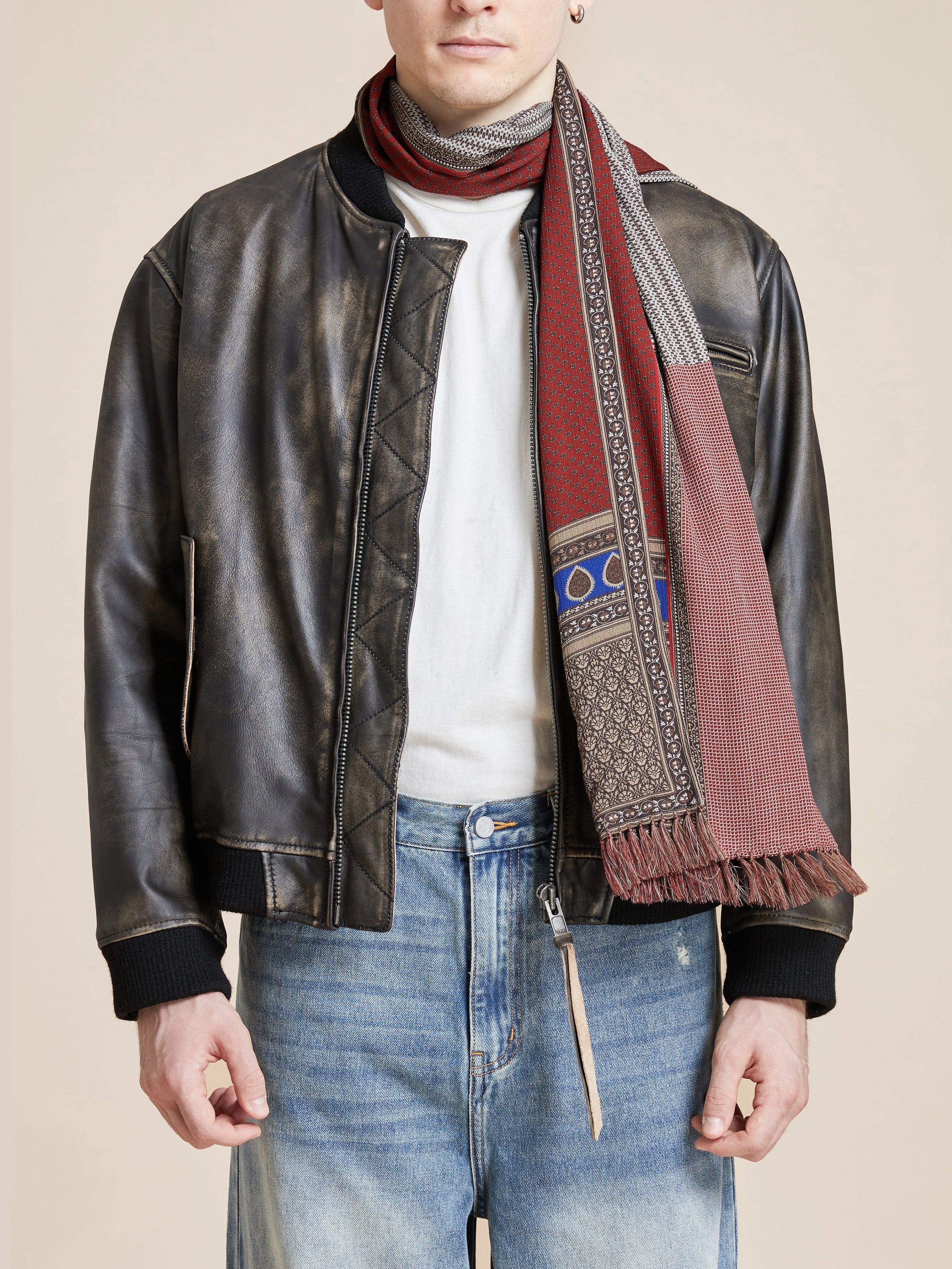 Dressed in a leather jacket, white shirt, and jeans, a person exudes effortless chicness with the Paisley Medley Scarf by Found elegantly wrapped around their neck.