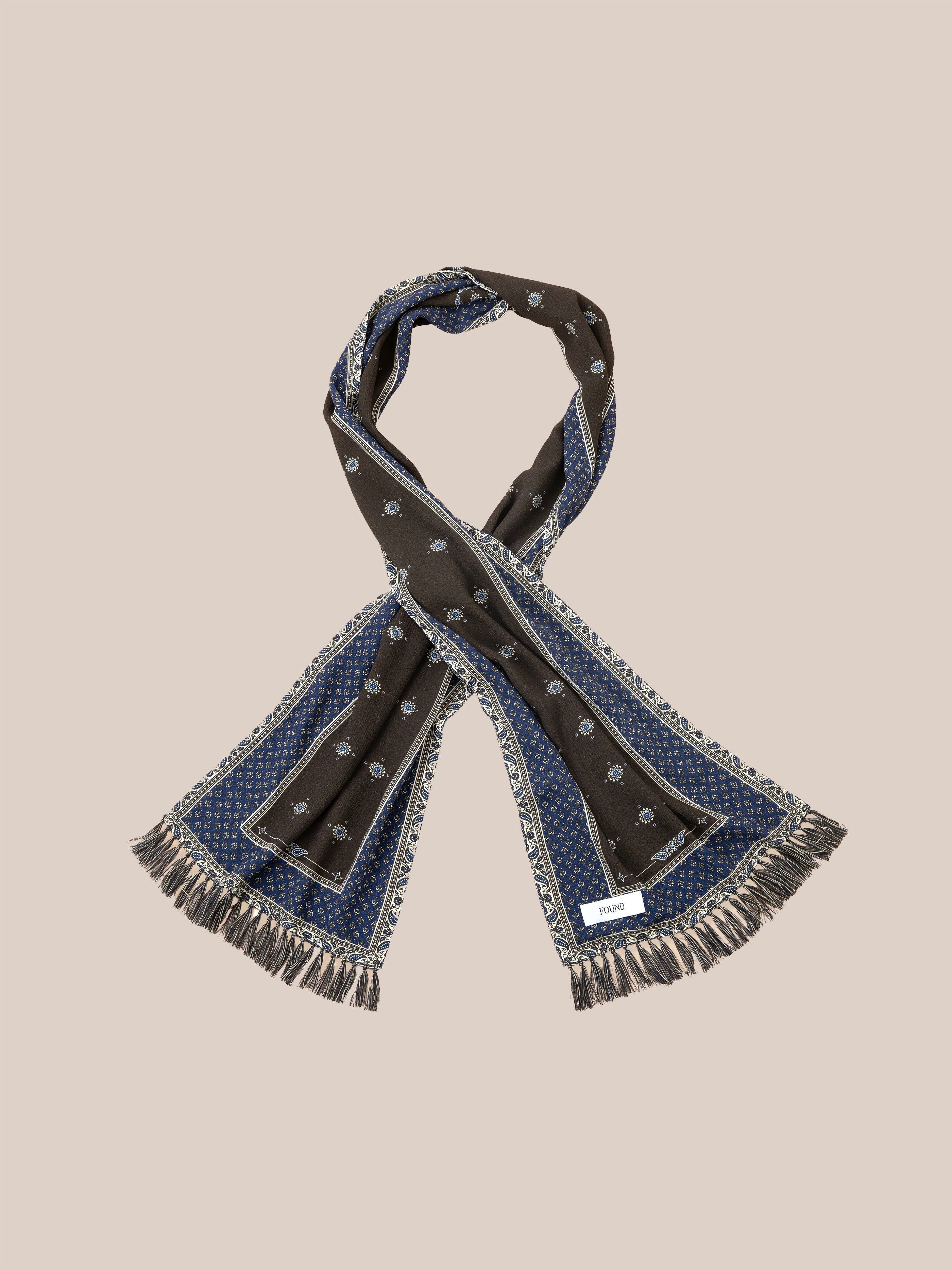 The Black Royal Blue Print Scarf by Found showcases a stylish design with sections of black and royal blue patterns, complete with hand-tied tassels and fringed edges.