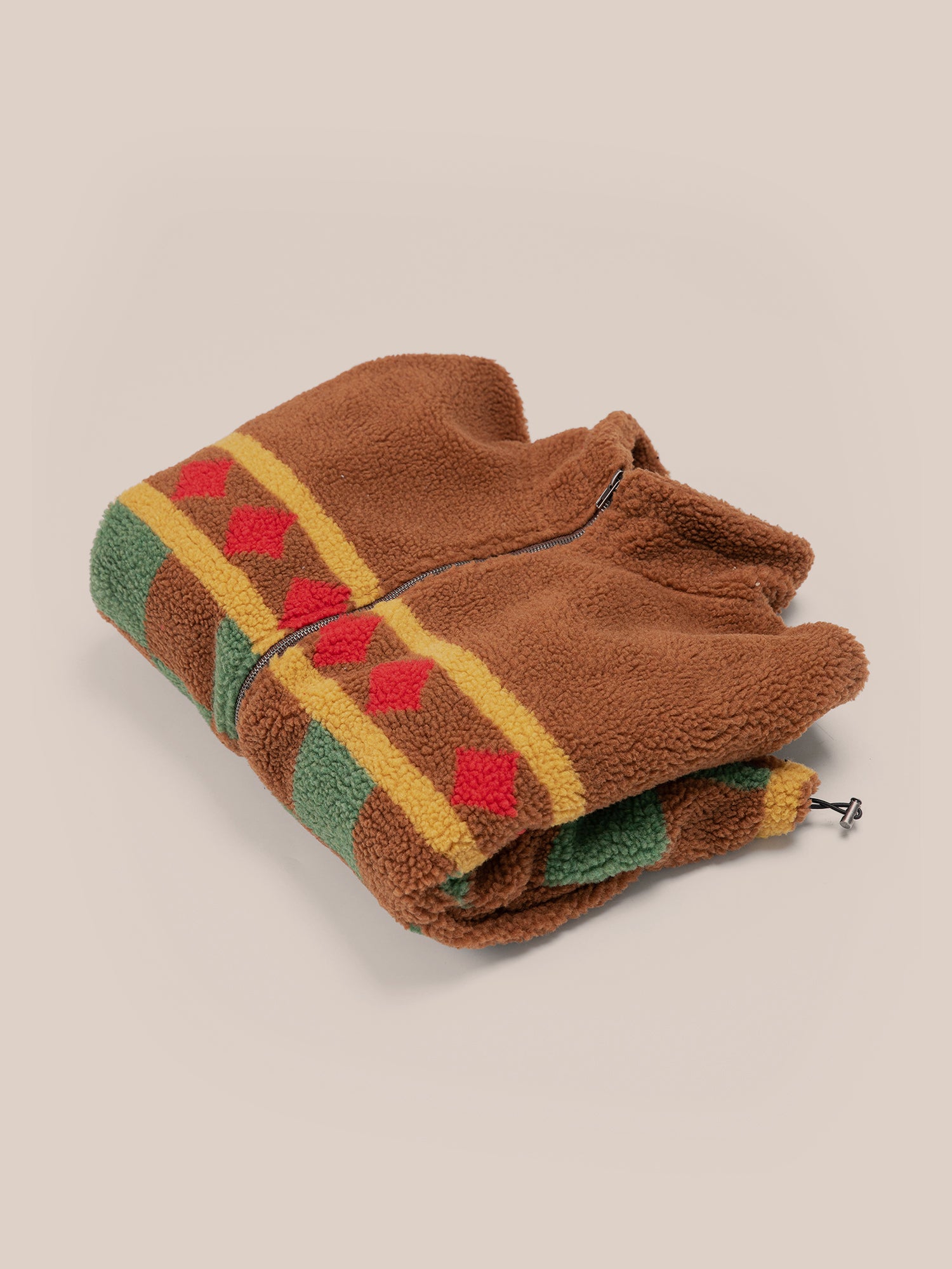 The folded Checkered Zip-Up Sherpa by FOUND features a colorful geometric pattern with red diamonds and green and yellow stripes, seamlessly integrating with its jacquard checkered design.