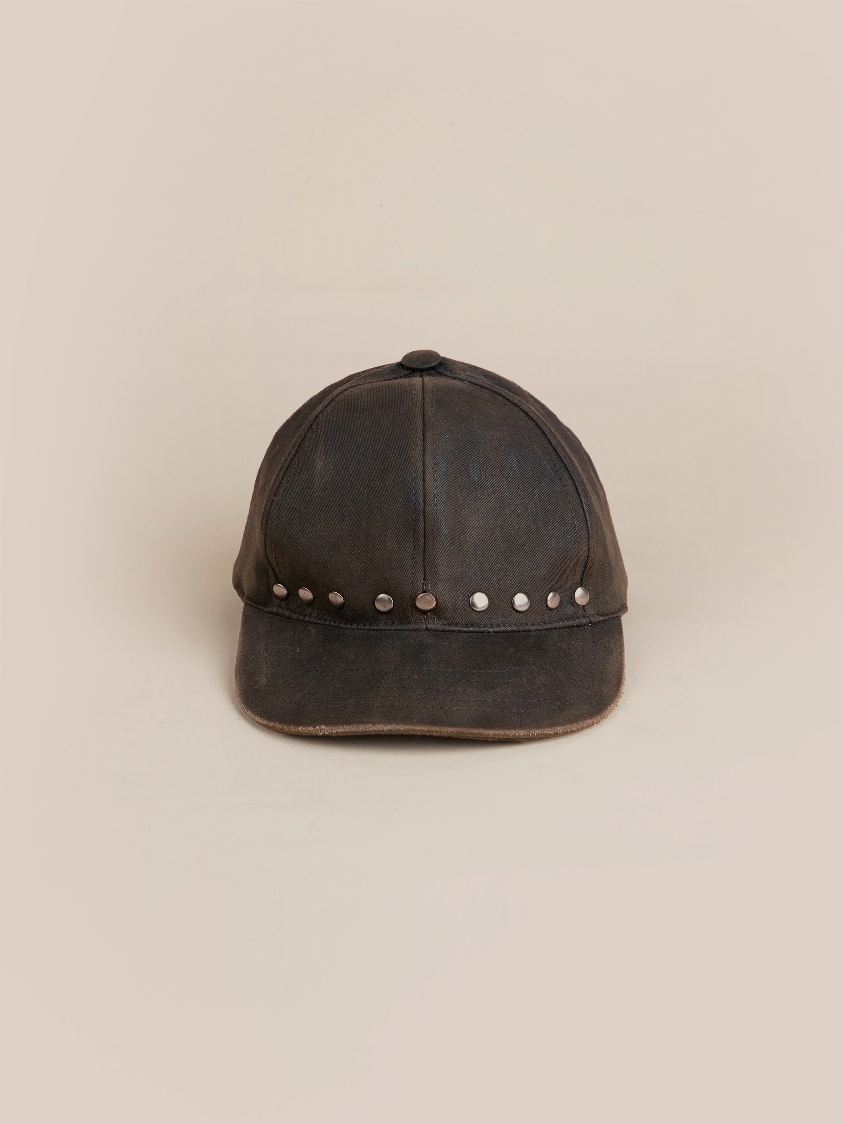 A distressed waxed charcoal cap by FOUND, featuring a row of silver studs across the front.